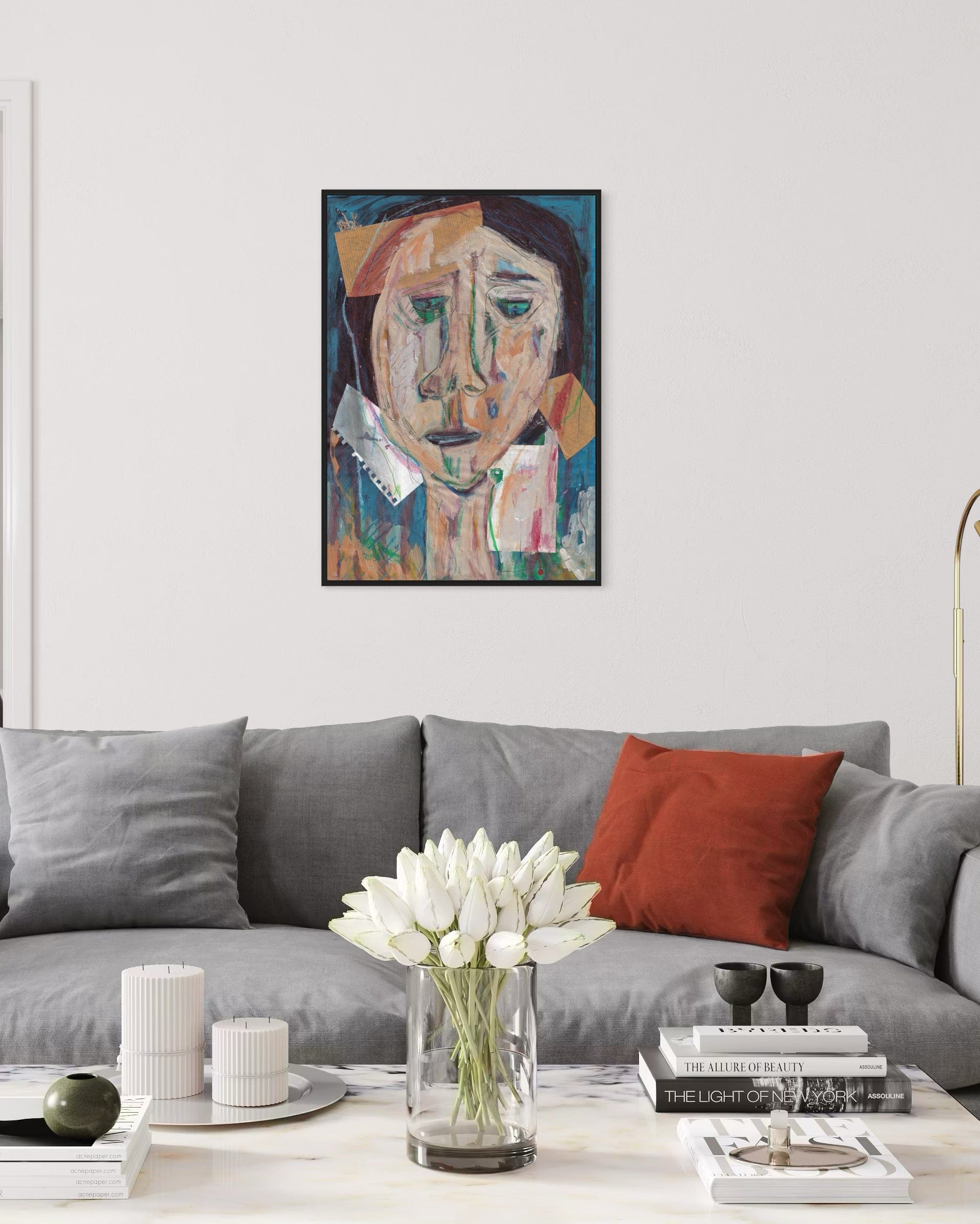 Living room with a gray sofa, red pillow, and a vase of white tulips on a coffee table. A framed painting hangs above the sofa.