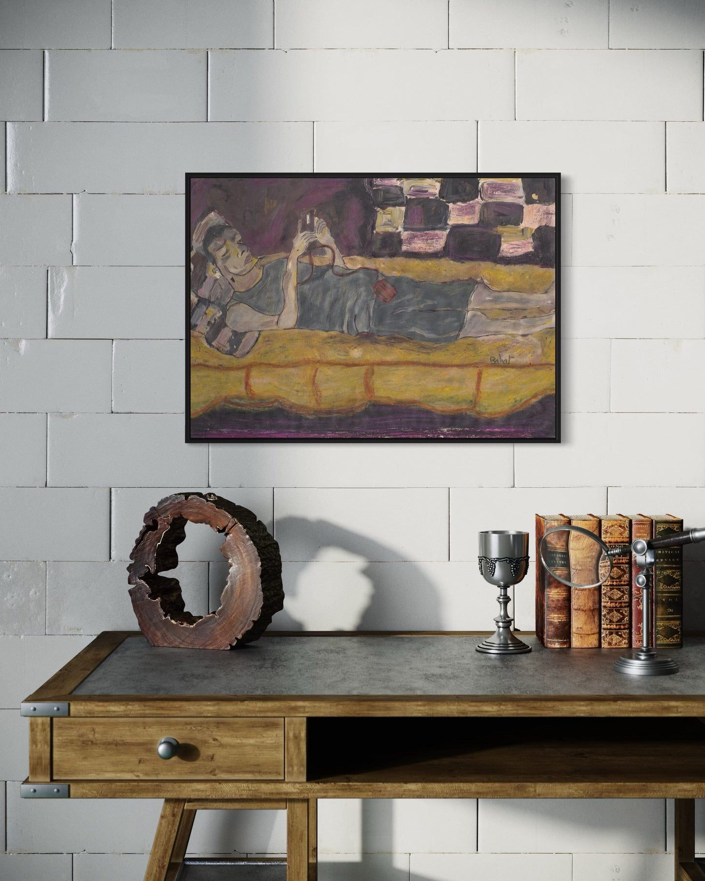 Framed artwork on a wall above a wooden table with decorative items.