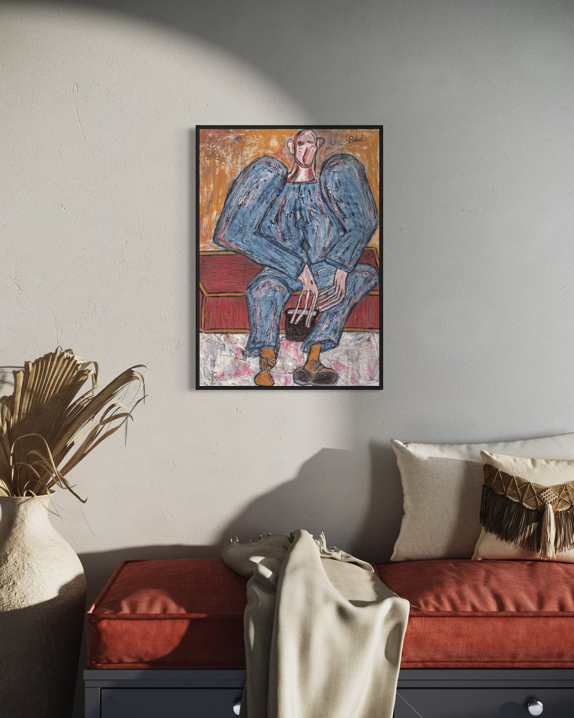 Framed artwork of a person sitting on a red couch in a living room setting.