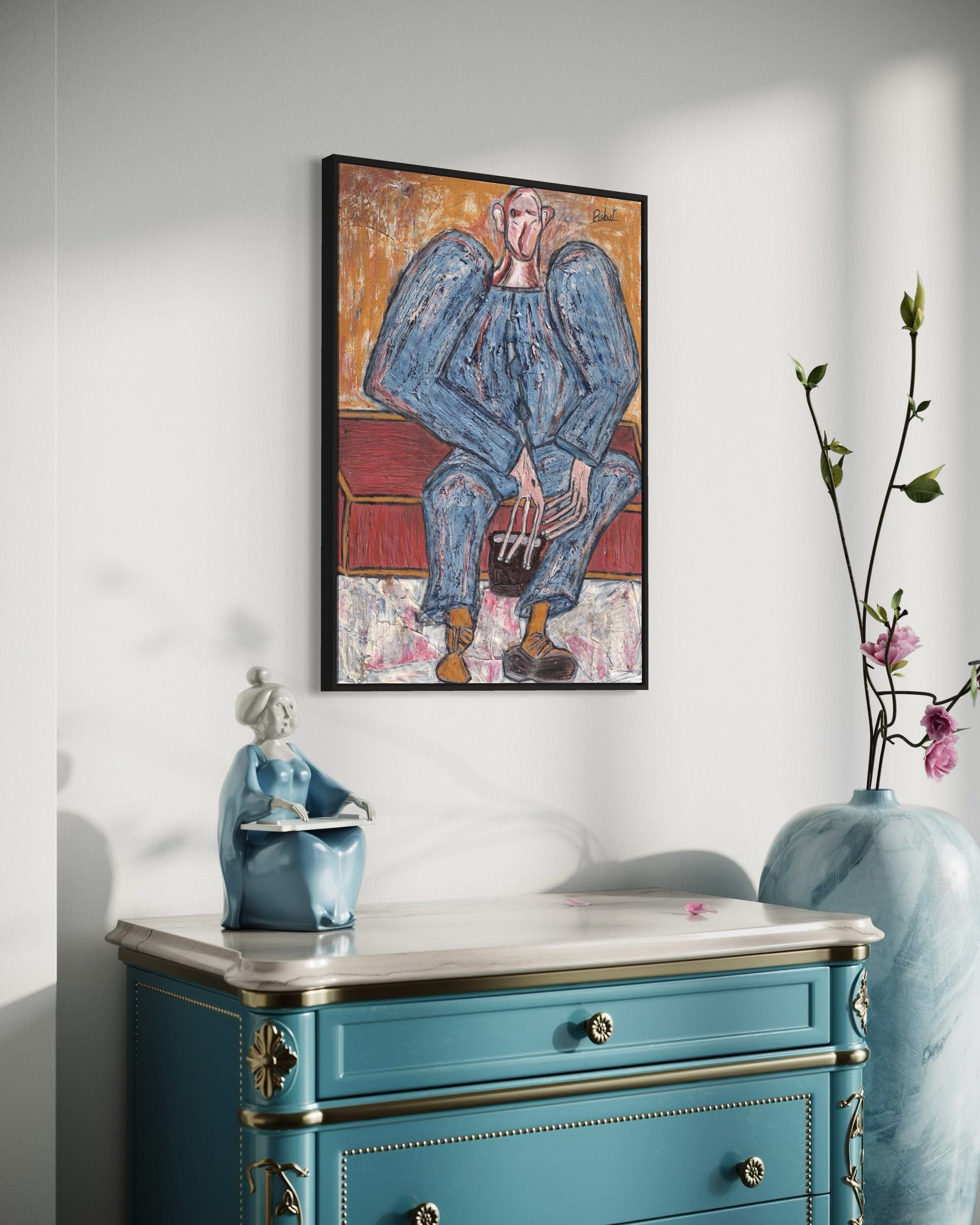 Framed artwork on a wall above a blue cabinet with decorative elements.