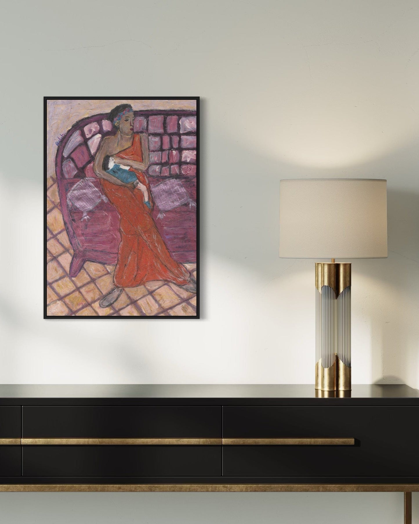 Framed artwork of a woman in a red dress on a wall above a black console table with a lamp.