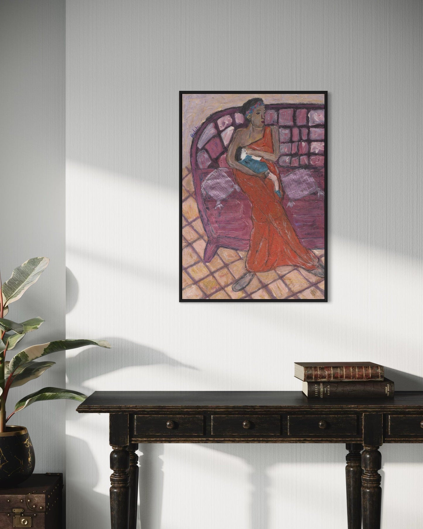 Framed artwork of a woman in a red dress on a white wall above a dark wooden table.