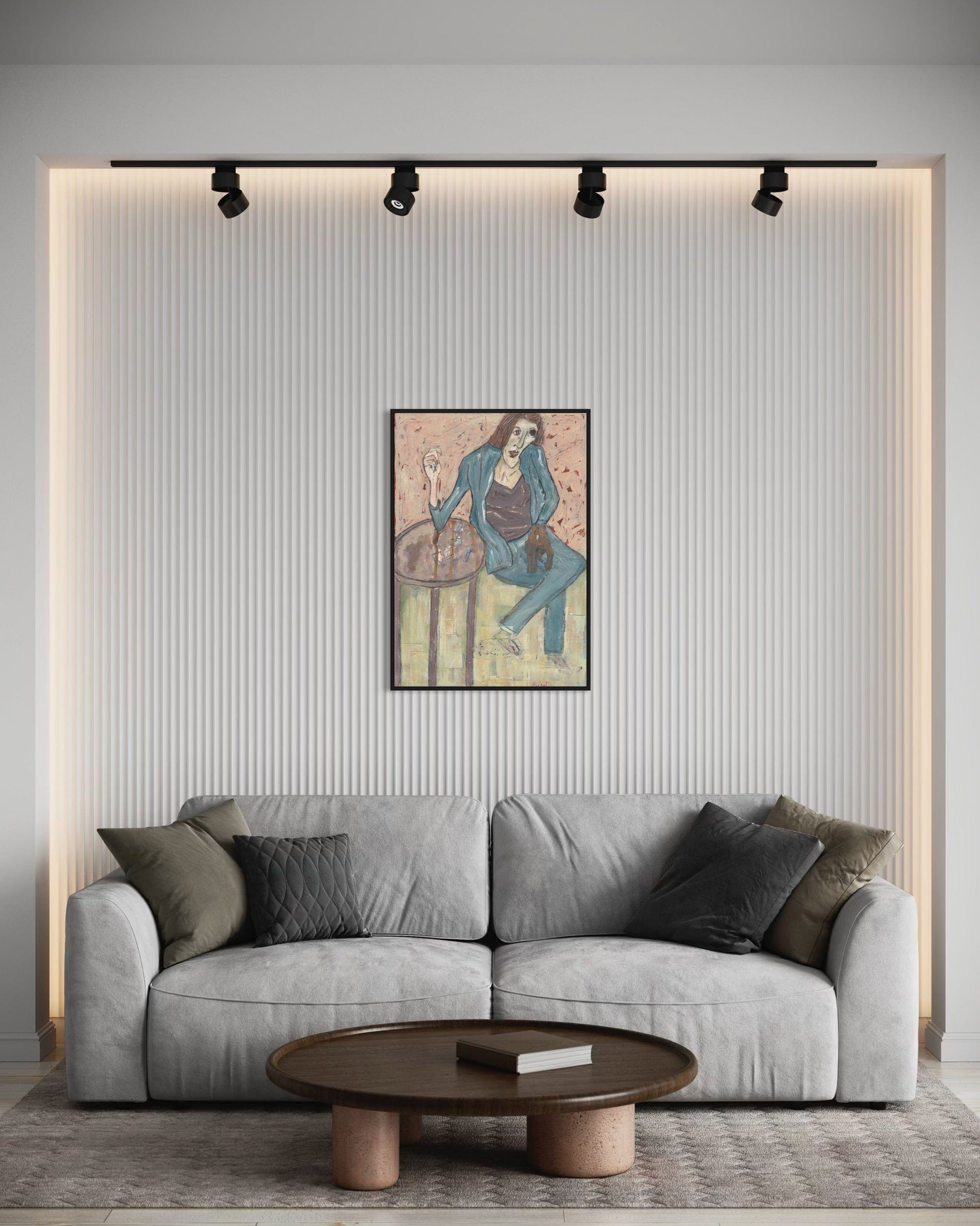 Gray sofa in a living room with a wall painting and round wooden coffee table.