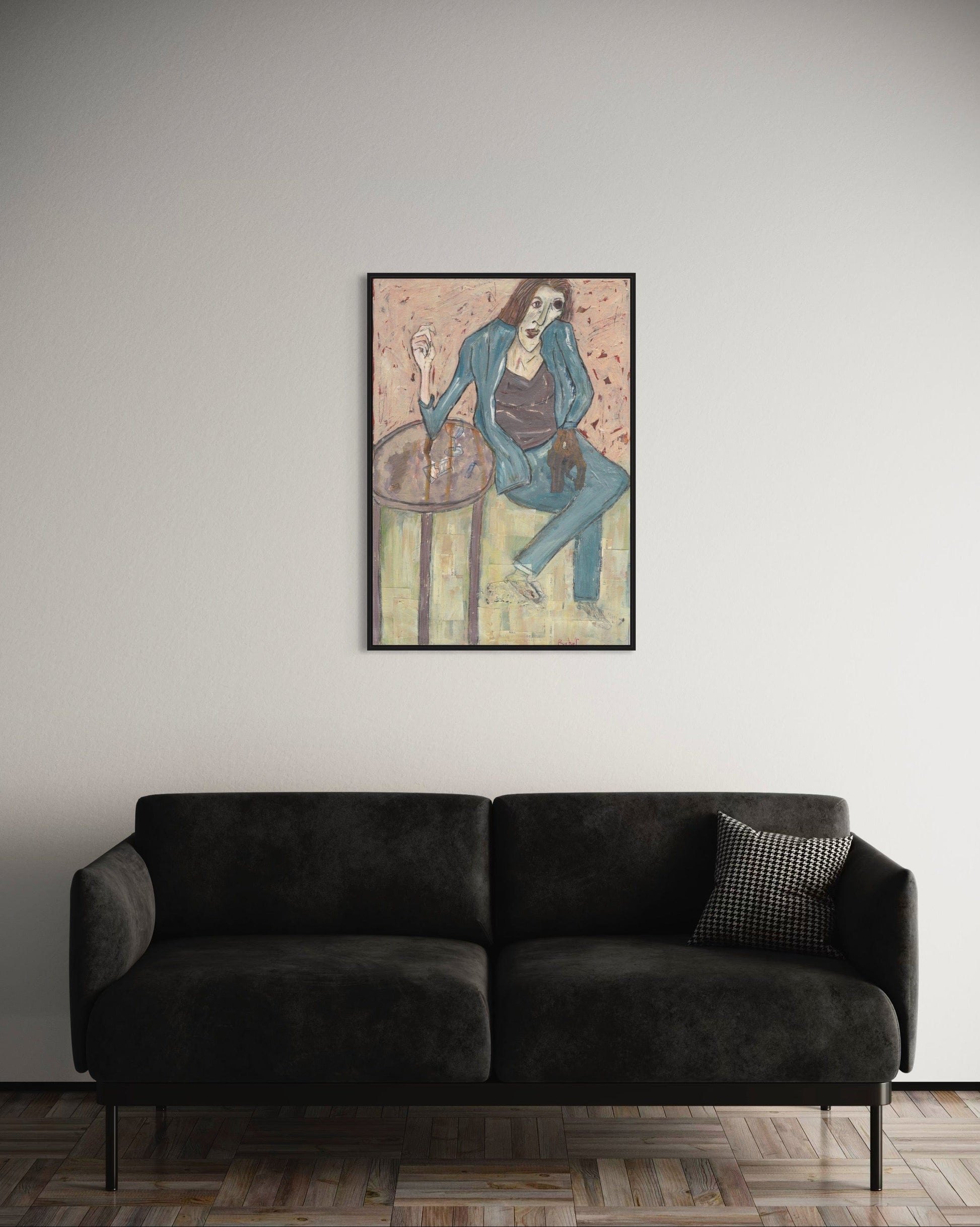 Framed artwork above a dark gray sofa in a room with a neutral wall.