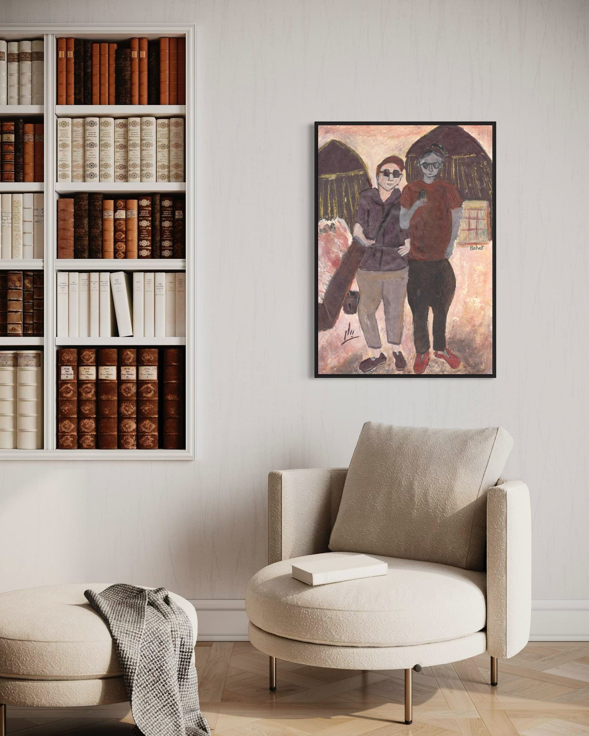 Living room with a bookshelf, armchair, and framed artwork on the wall.