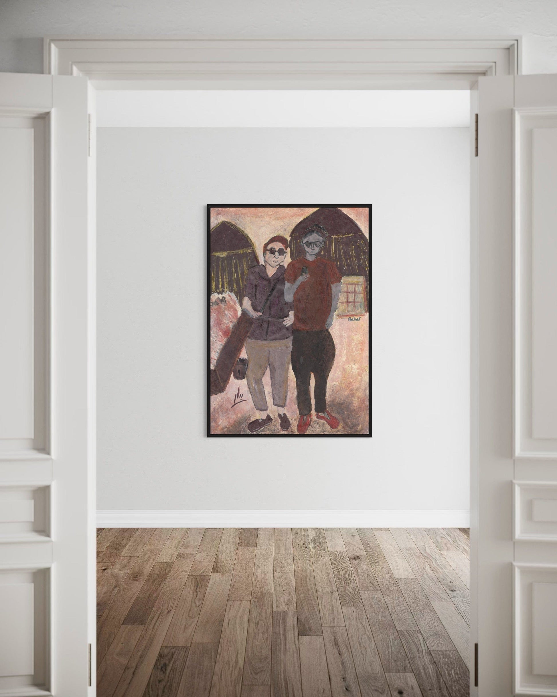 Framed artwork of two people standing together on a wall in a room with wooden flooring.