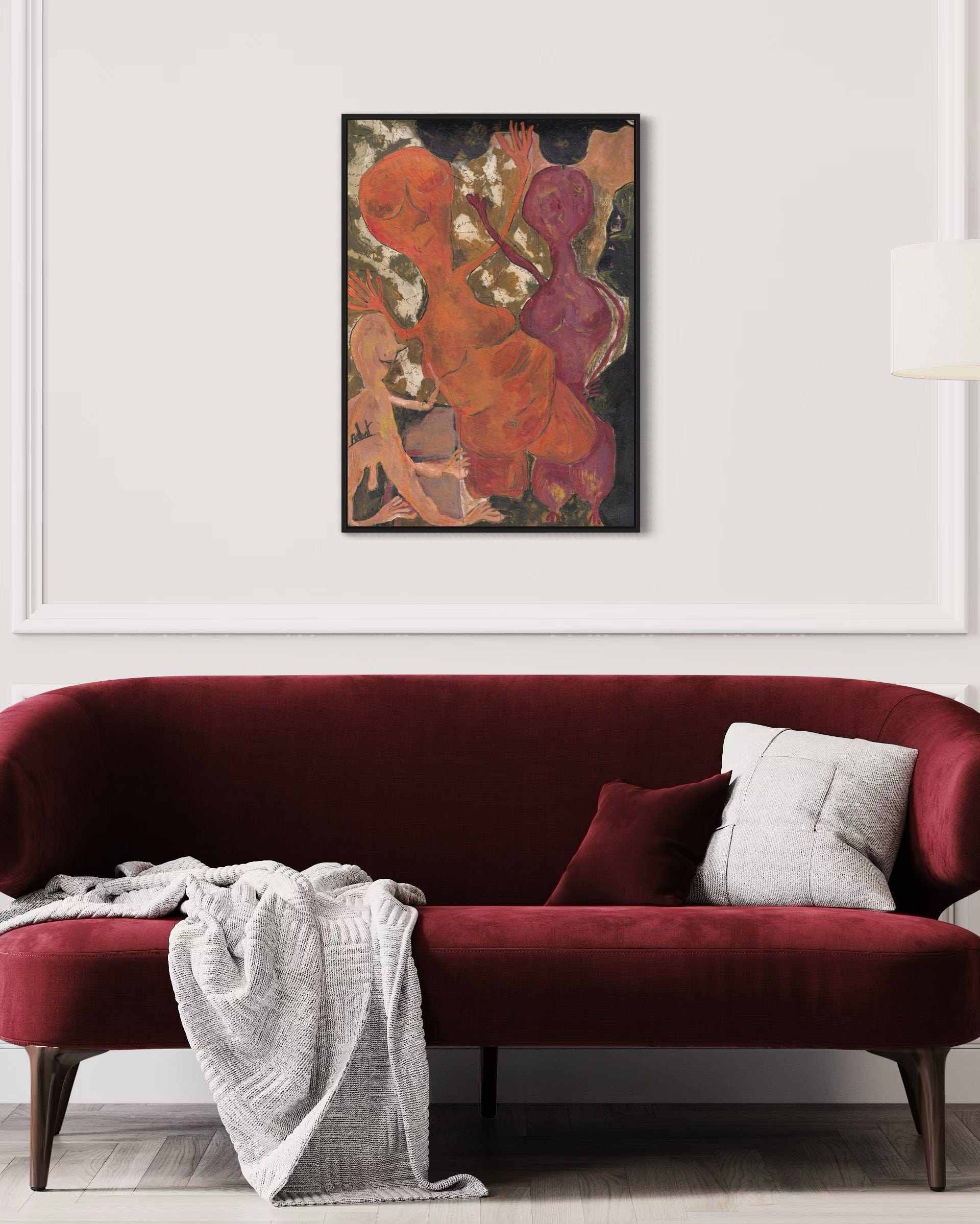 Red sofa with a white blanket and gray pillow in front of a colorful abstract painting on a white wall.