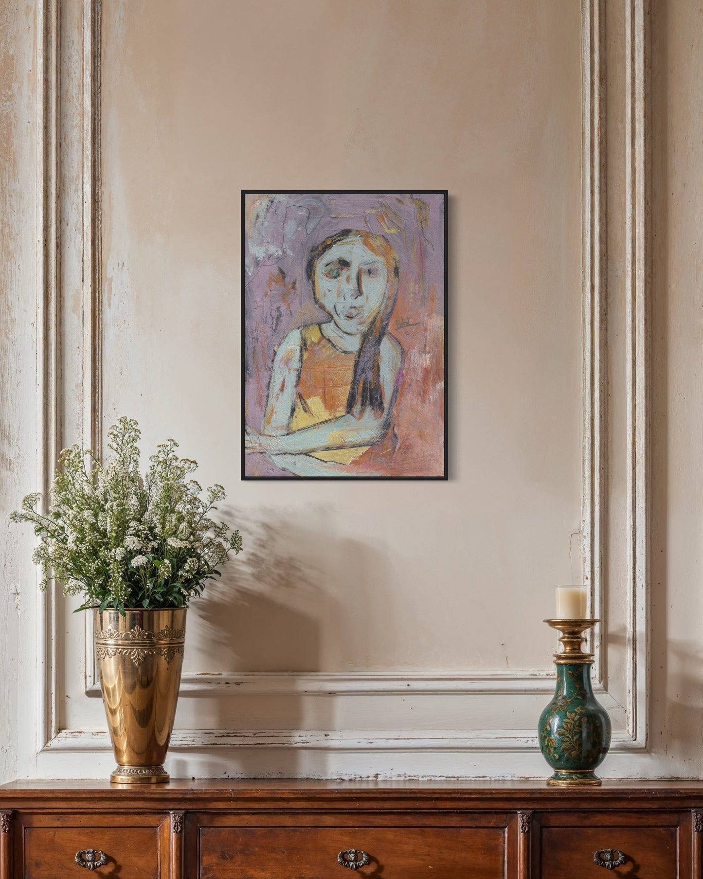 Framed abstract painting of a woman on a wall above a wooden console table with decorative items.