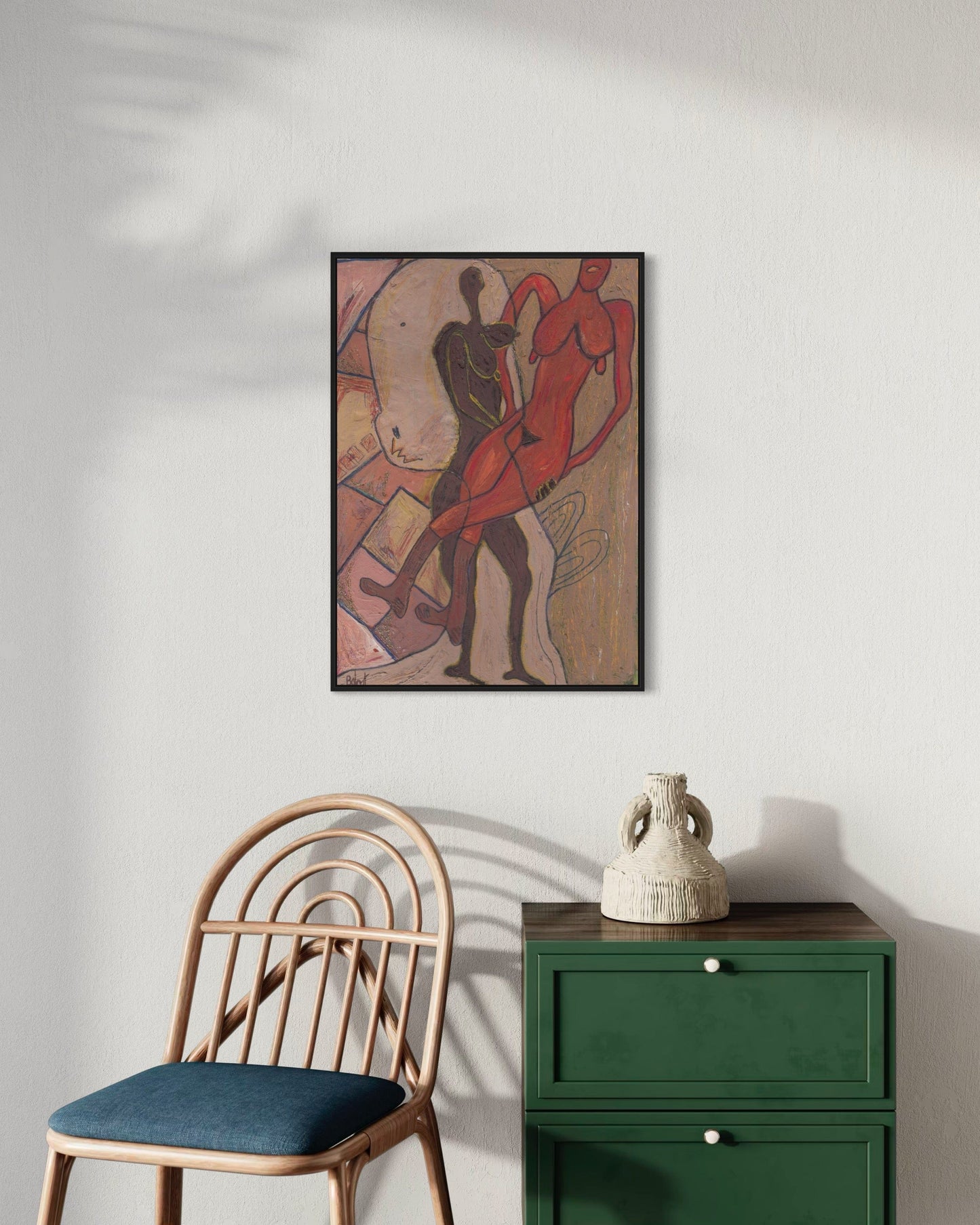 Framed artwork on a wall above a chair and green cabinet
