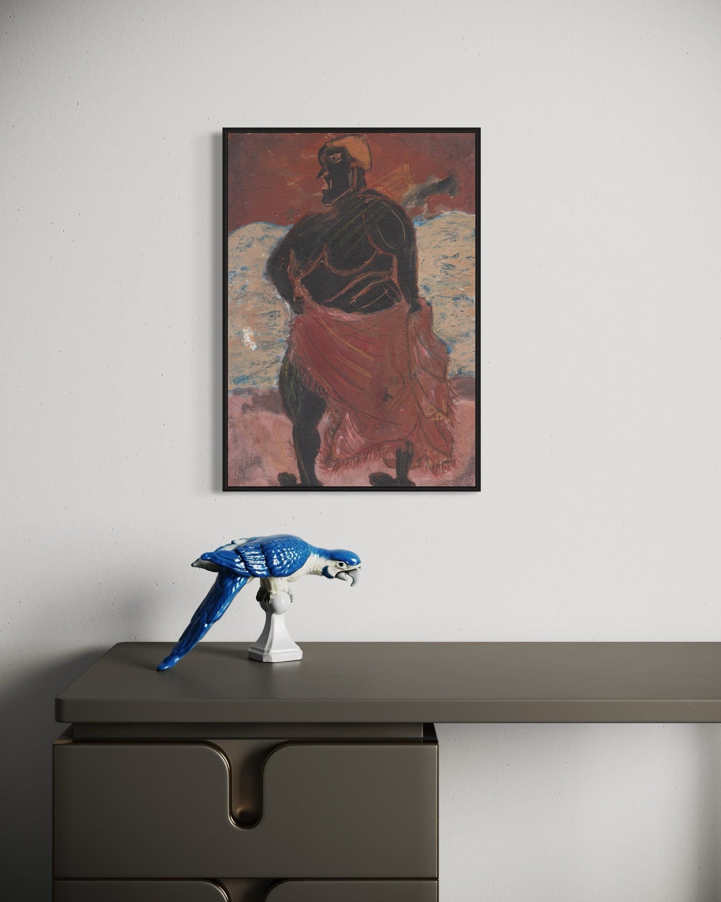 Framed artwork of a figure on a wall above a desk with a blue sculpture.