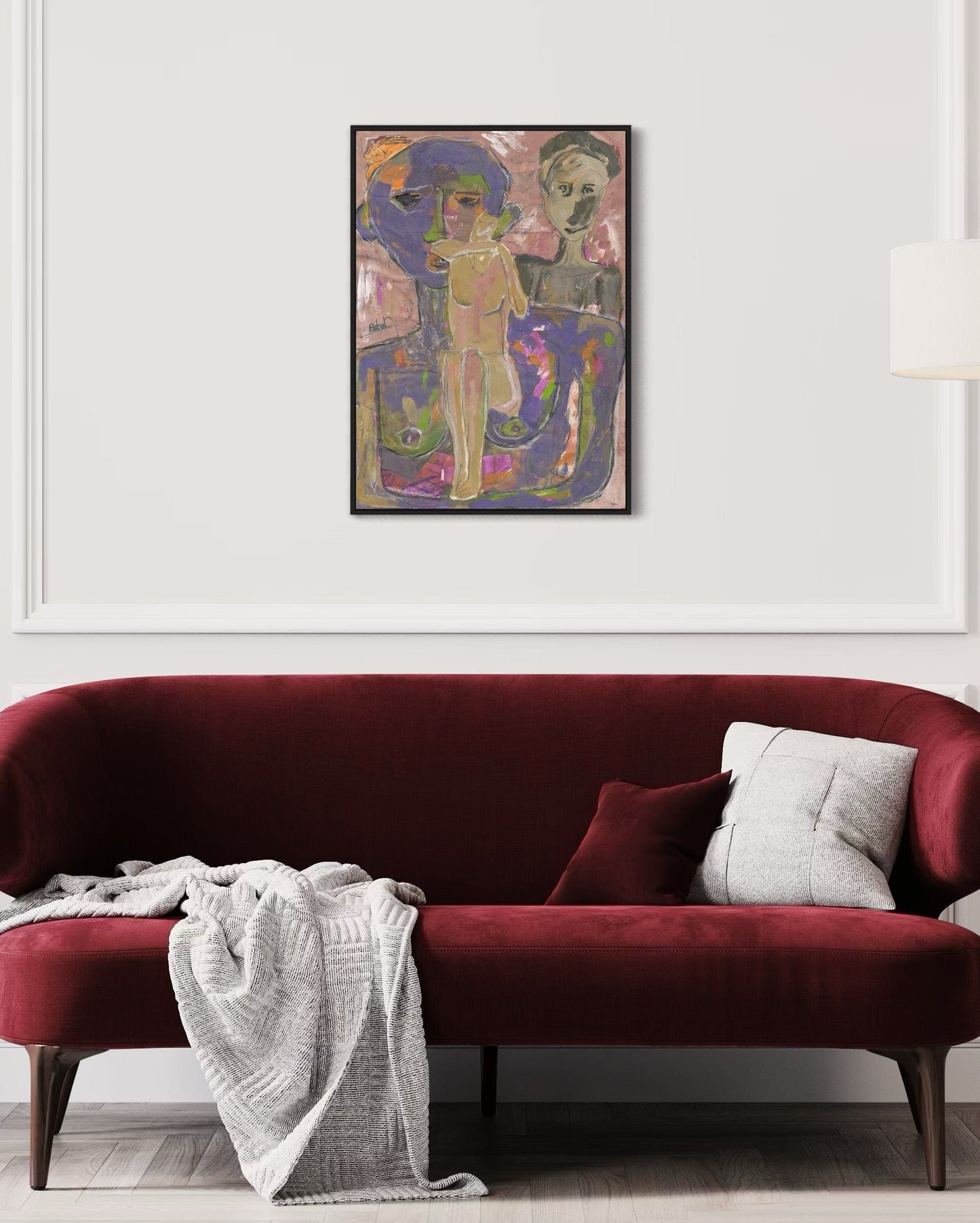 Red sofa with a white blanket and gray pillow, framed artwork above on a white wall.