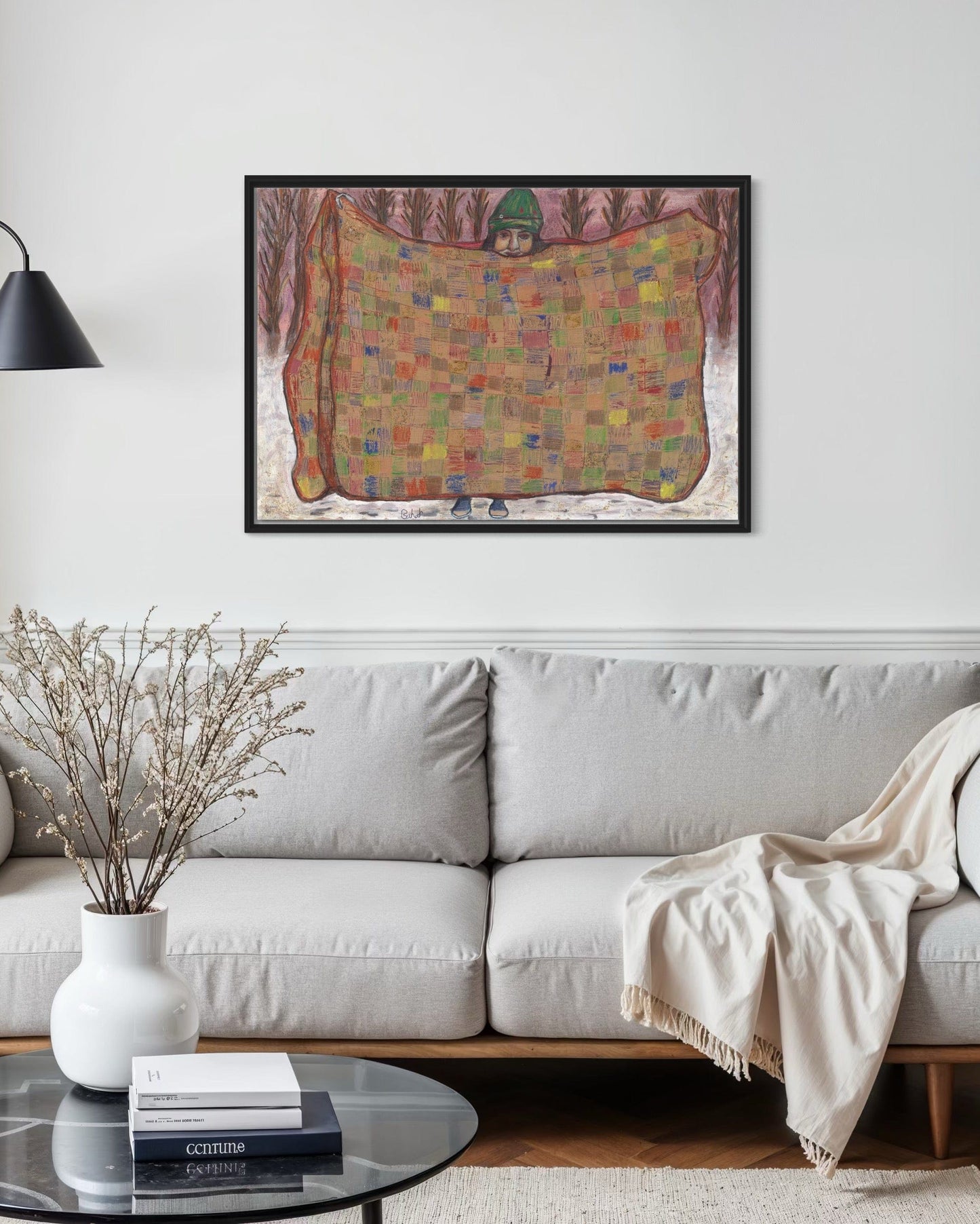 Living room with a gray sofa, decorative vase, books, and a colorful map on the wall.