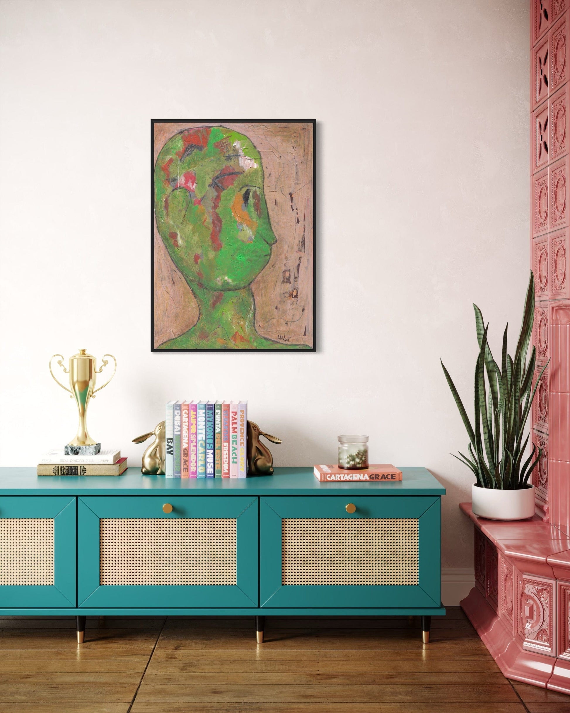 Teal console table with decorative items against a white wall with a framed artwork of a green face.