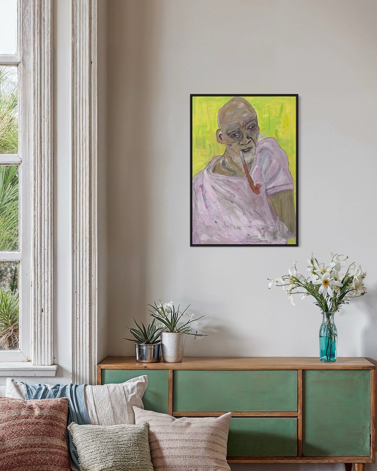 Living room with a painting of a bald man on the wall above a green cabinet.