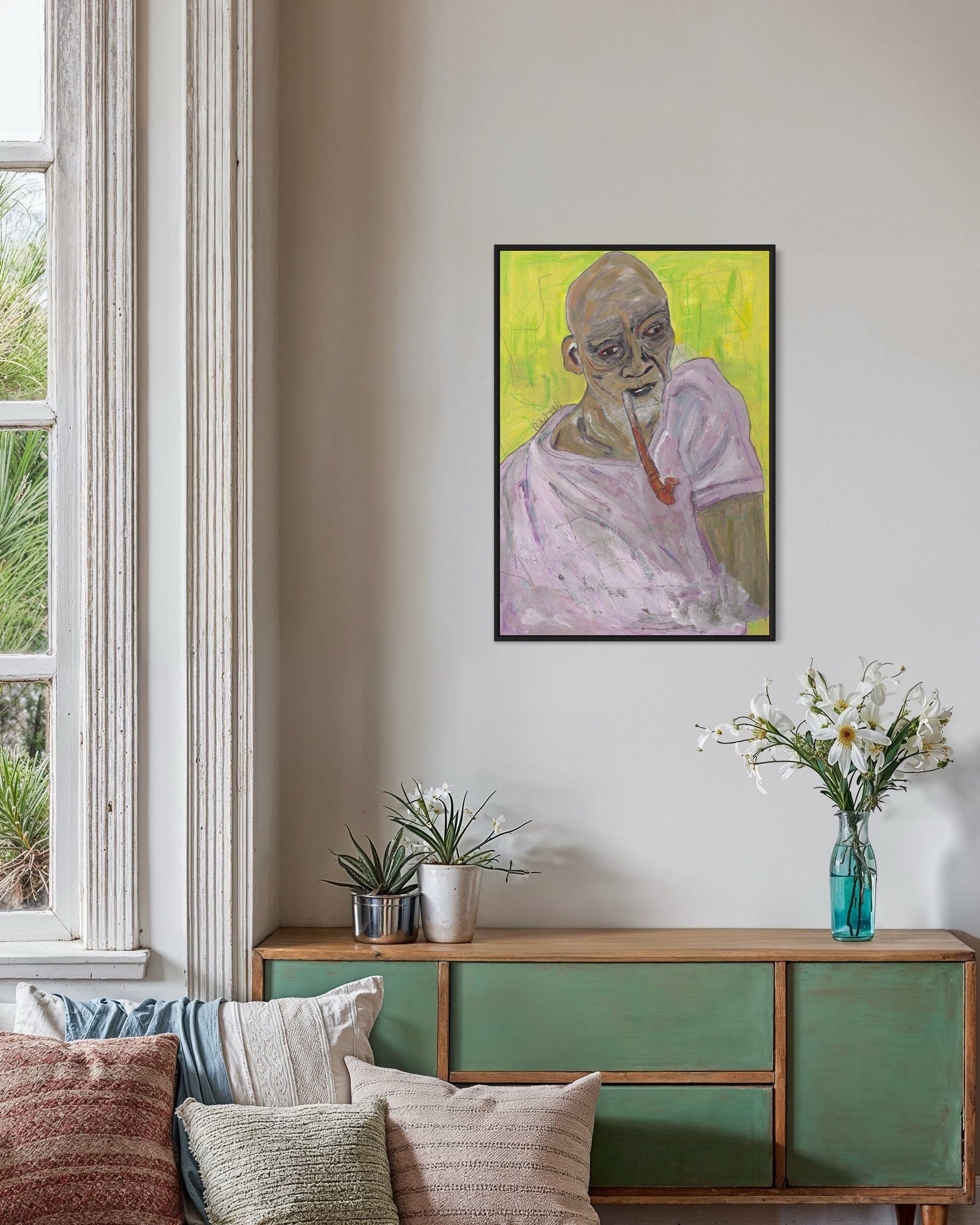 Living room with a painting of a bald man on the wall above a green cabinet.