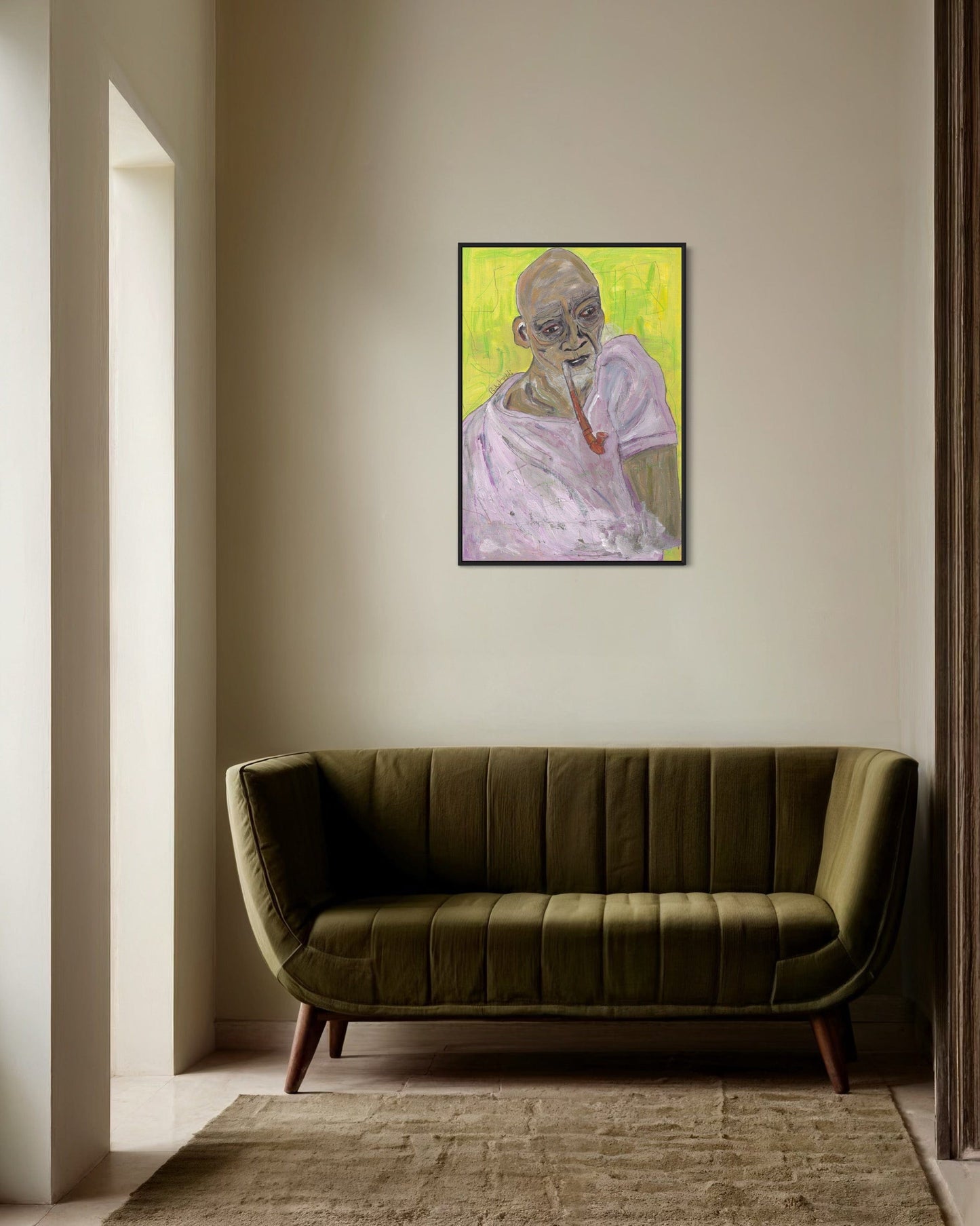 Framed portrait on a wall above a green sofa in a room with neutral decor.