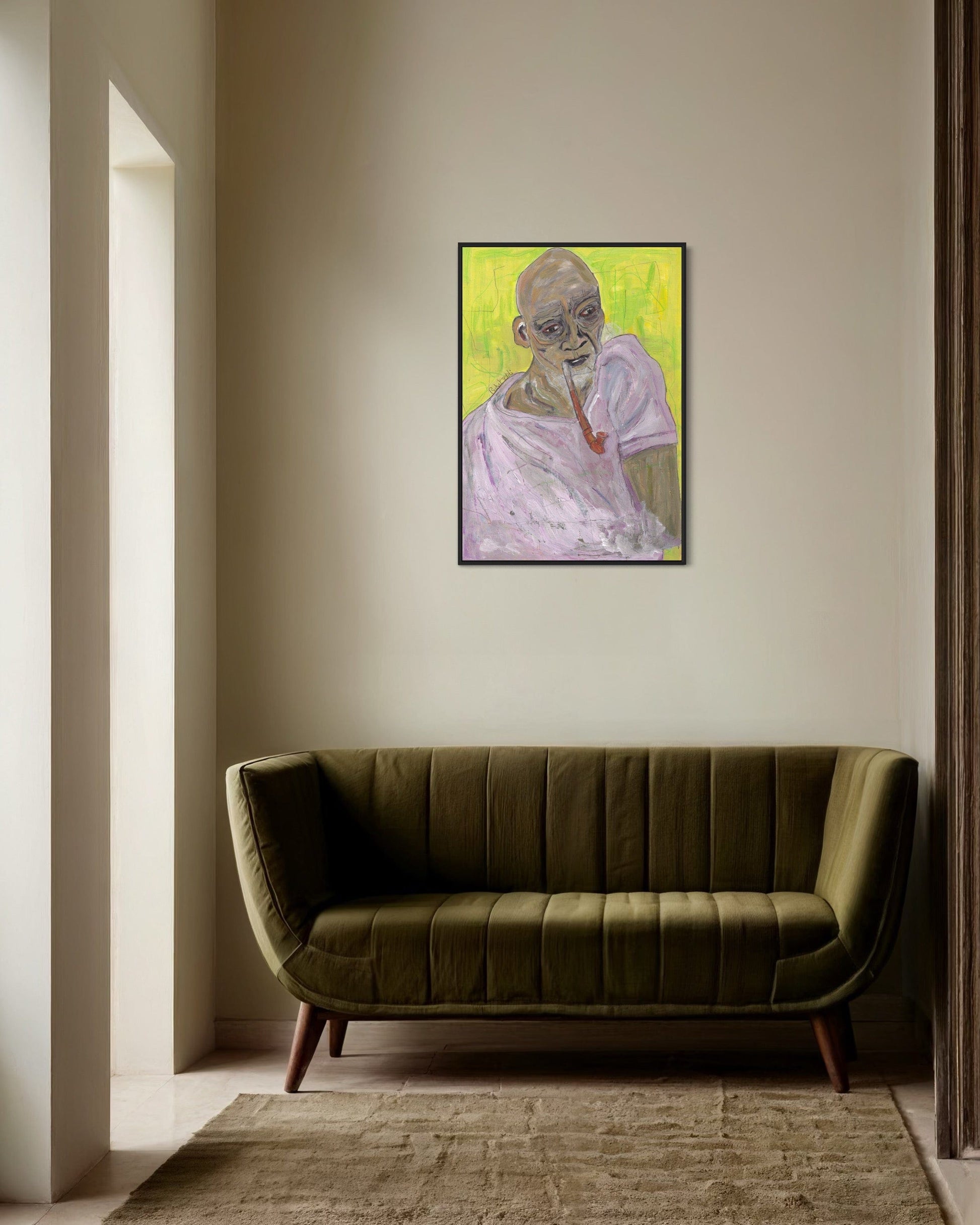 Framed portrait on a wall above a green sofa in a room with neutral decor.
