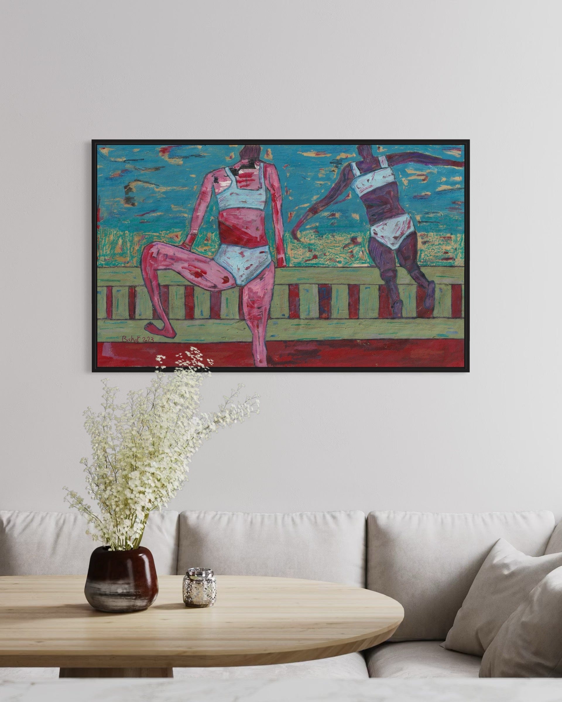Colorful abstract painting of two figures on a wall above a sofa and coffee table.