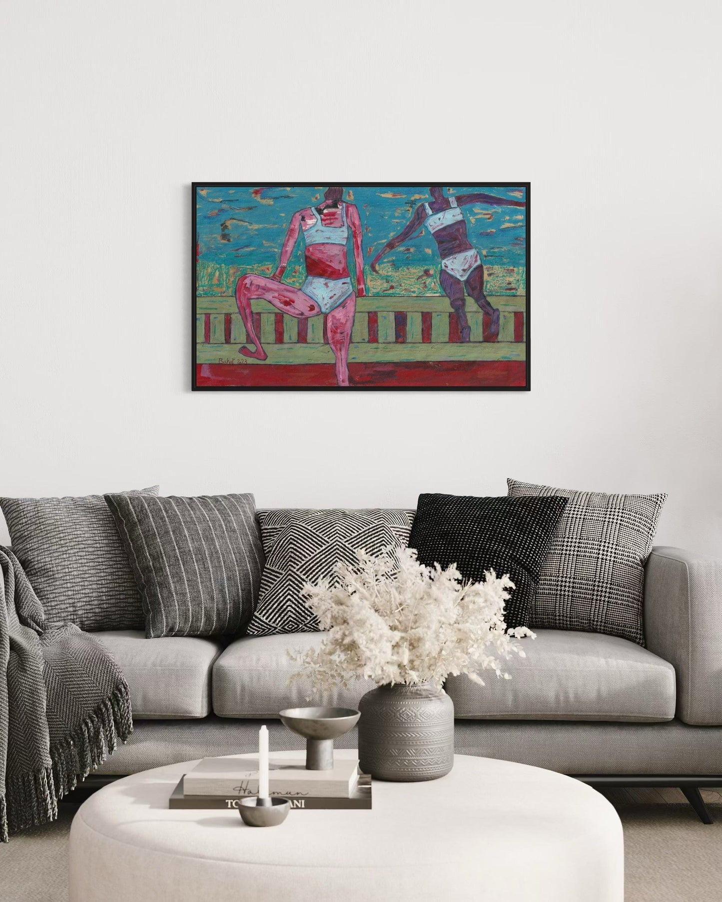 Framed artwork of two figures on a wall above a sofa with decorative pillows.