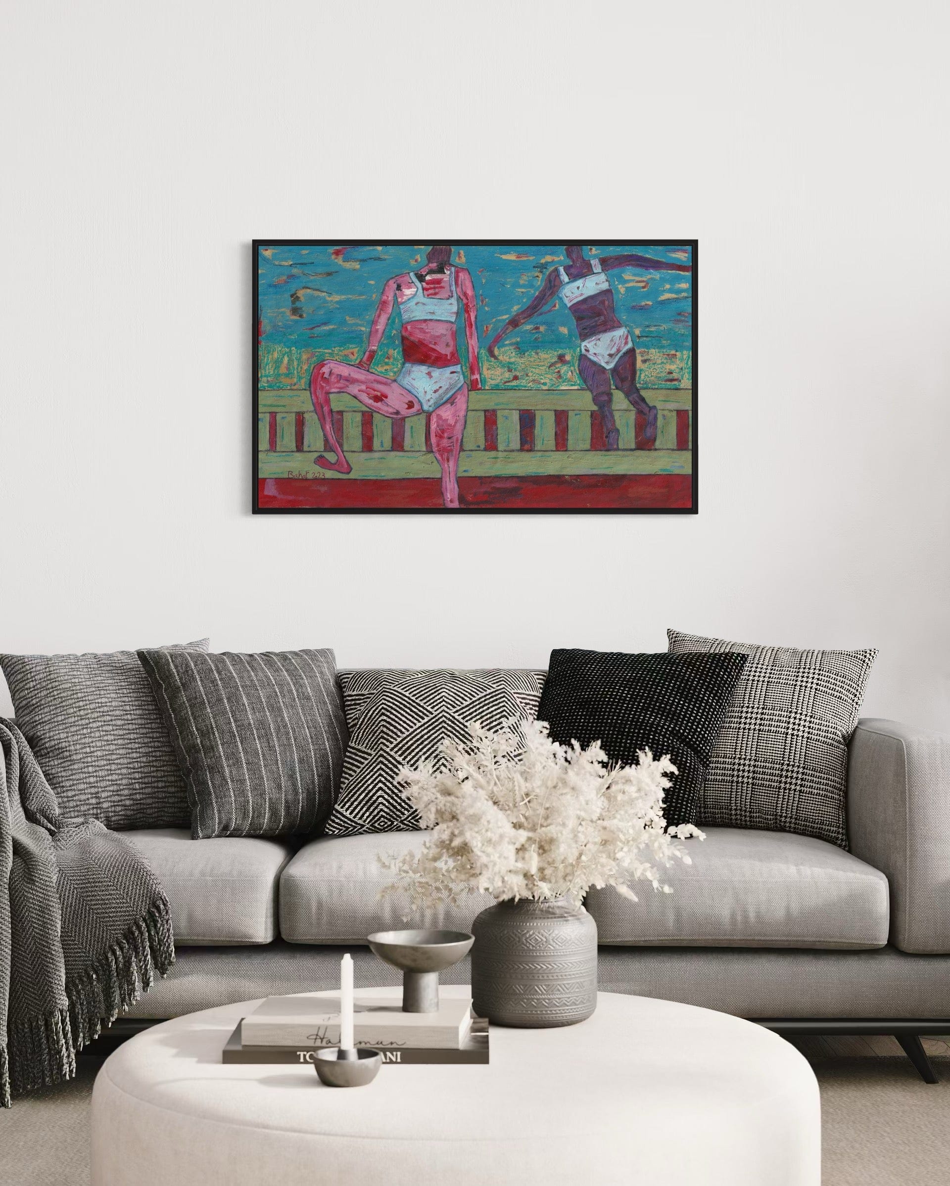 Framed artwork of two figures on a wall above a sofa with decorative pillows.