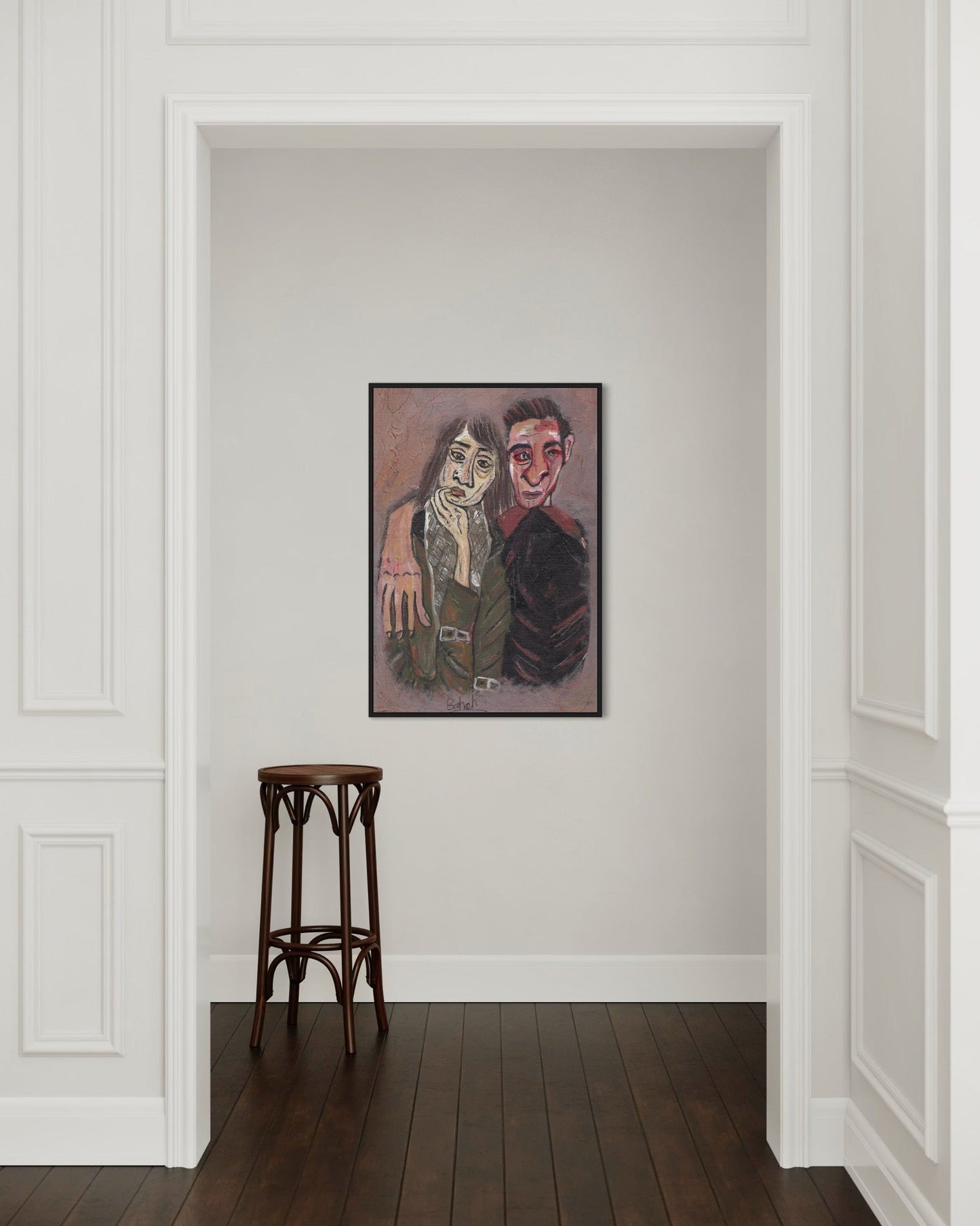 Framed artwork on a wall with a wooden stool in front