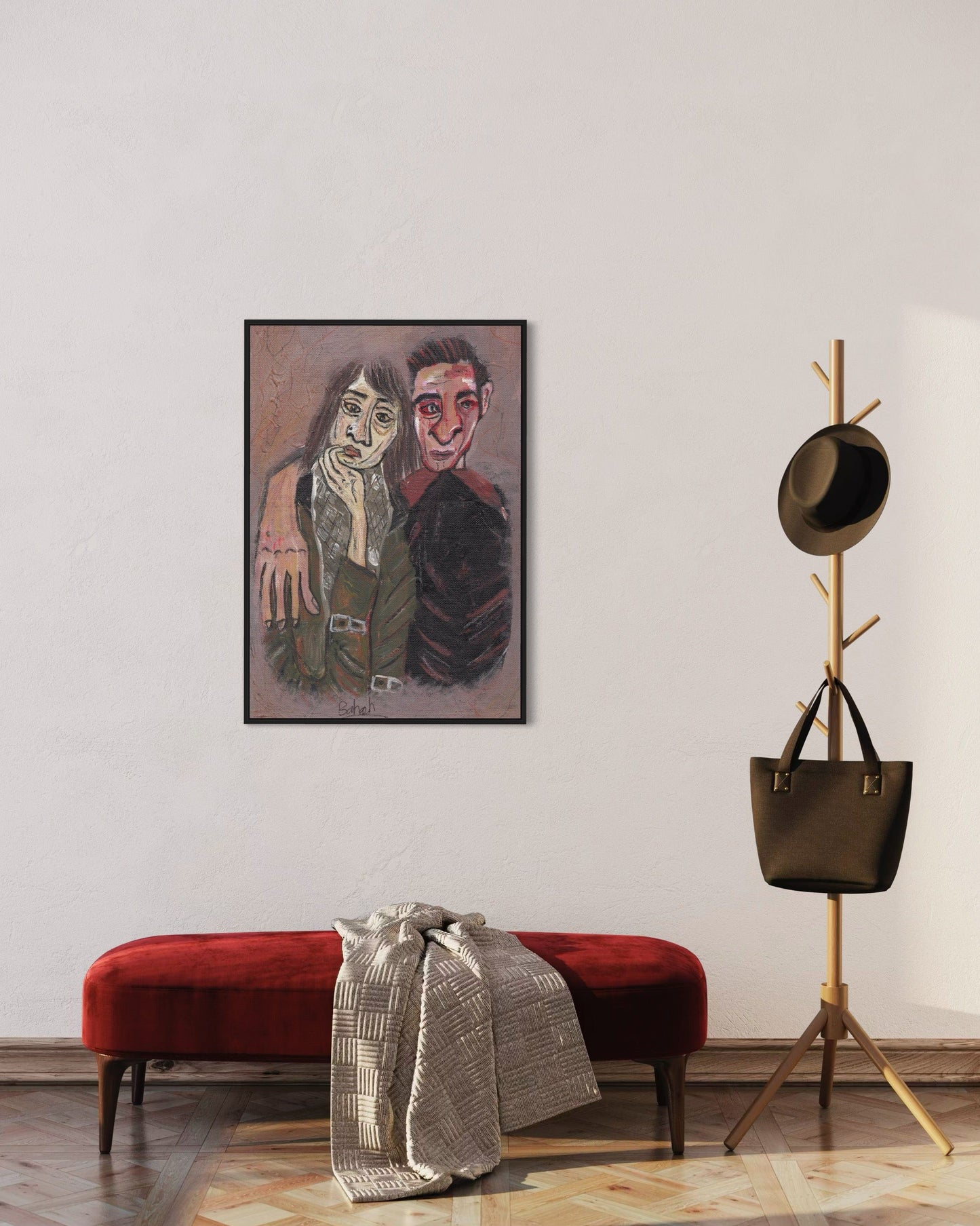 Framed artwork of two people on a wall above a red bench with a coat rack and bag in the corner.