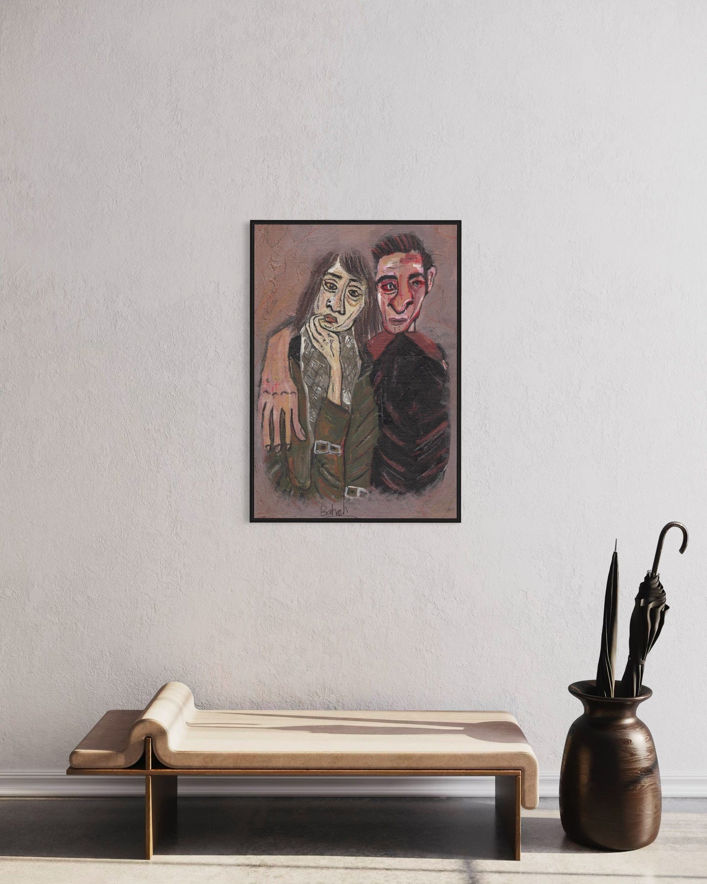 Framed artwork of two people on a wall above a wooden bench and vase with an umbrella.