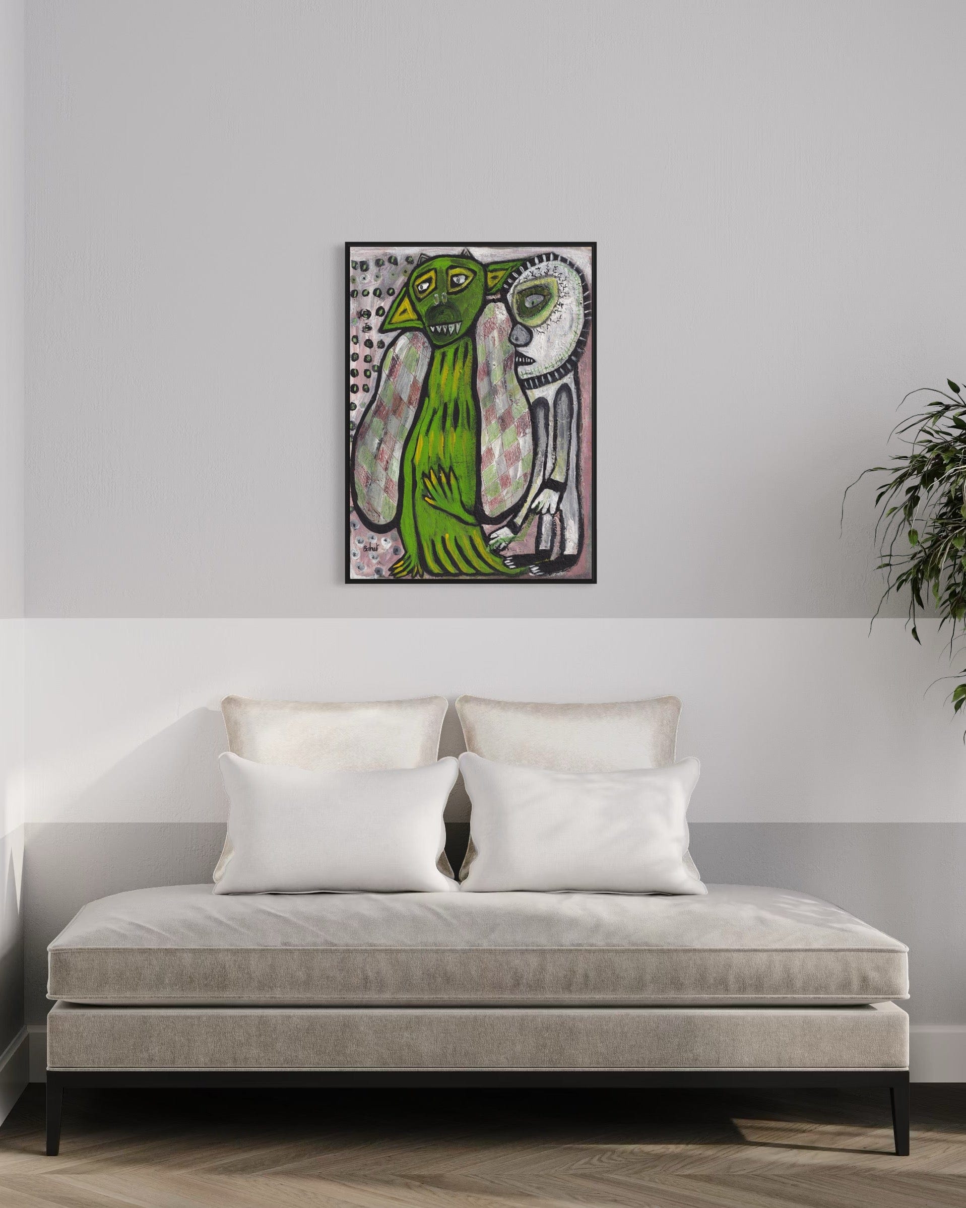 Framed artwork of two green creatures on a wall above a sofa.