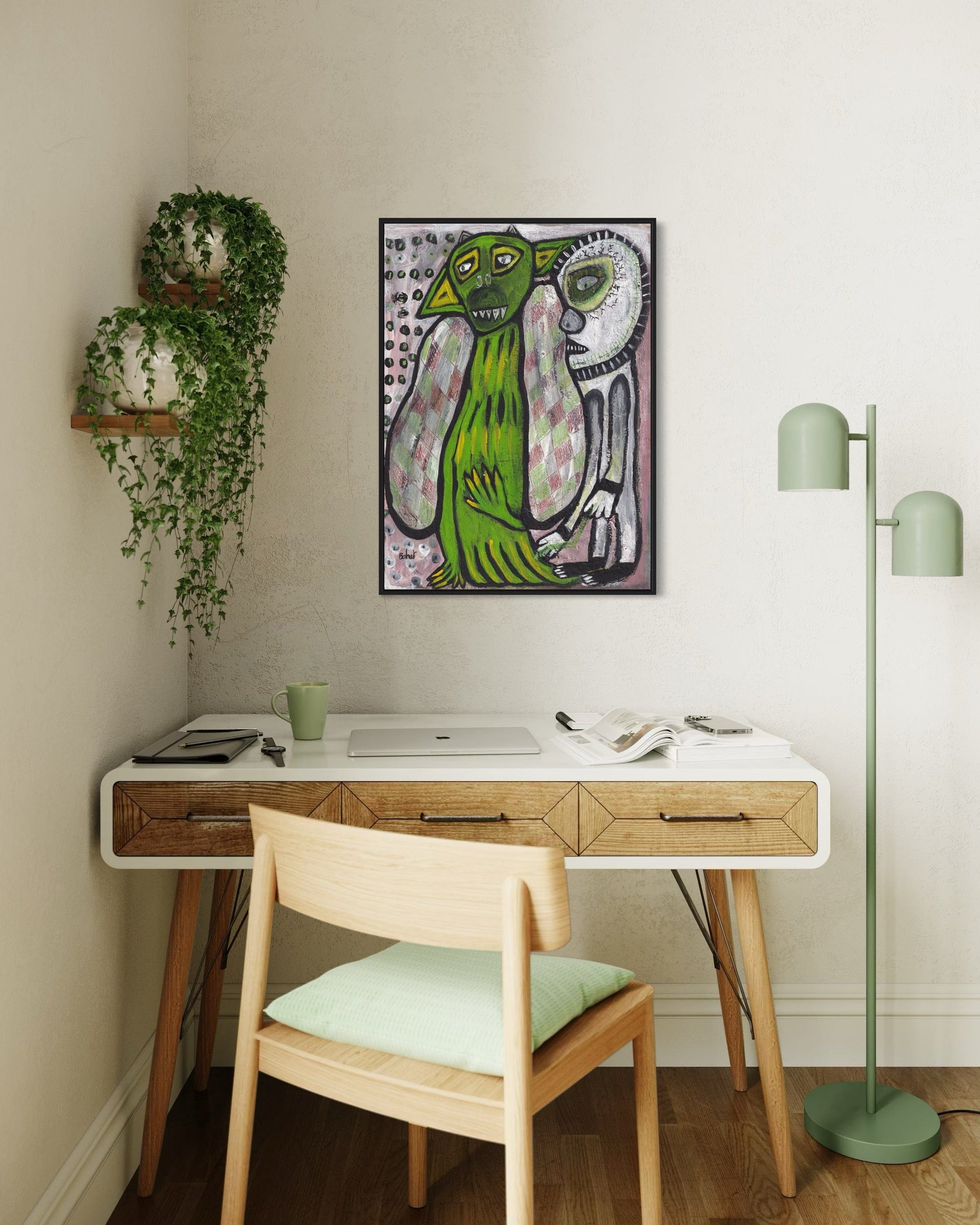 Home office with a desk, chair, lamp, and wall art of a green cat.