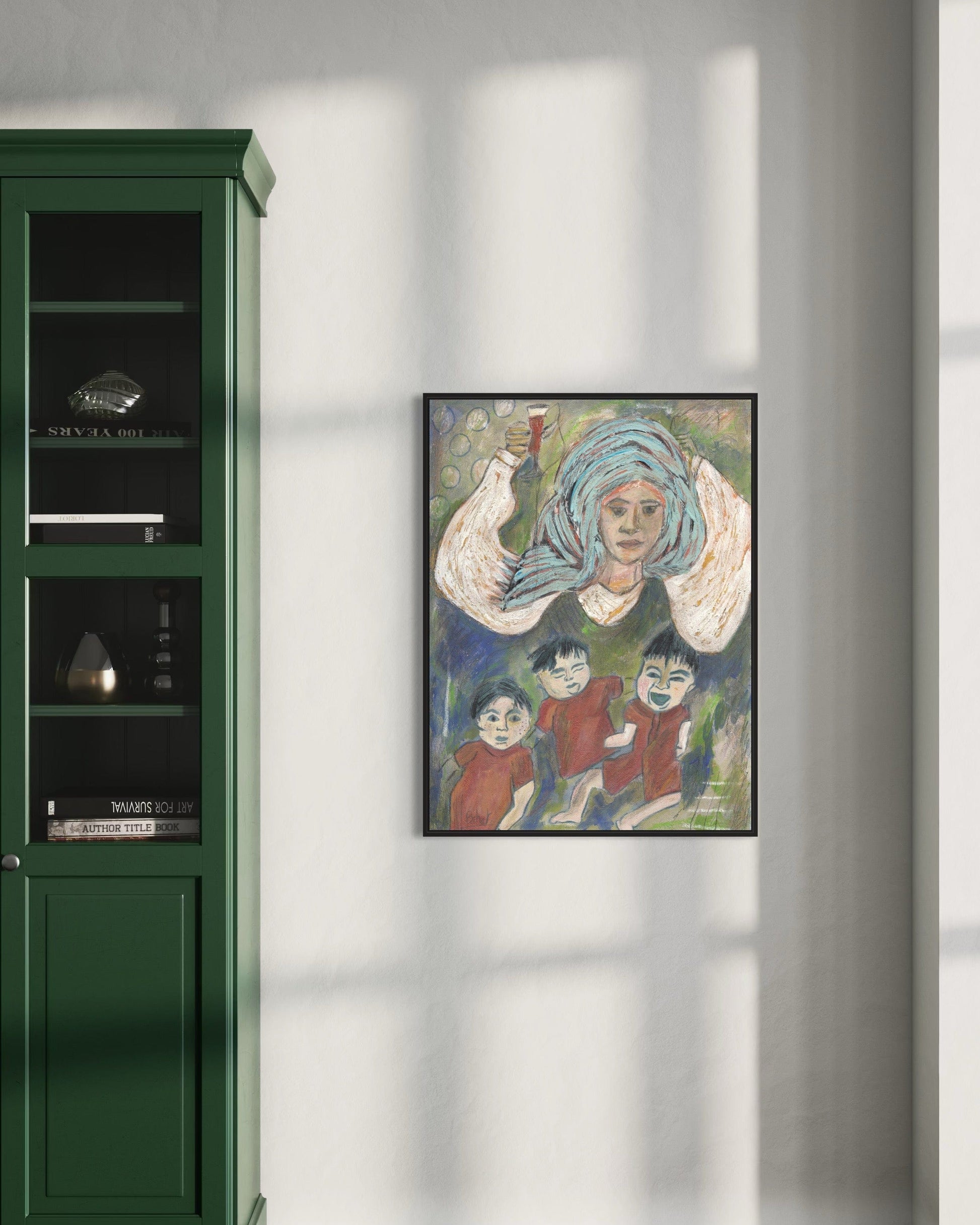 Framed artwork of a woman with children on a wall next to a green cabinet.