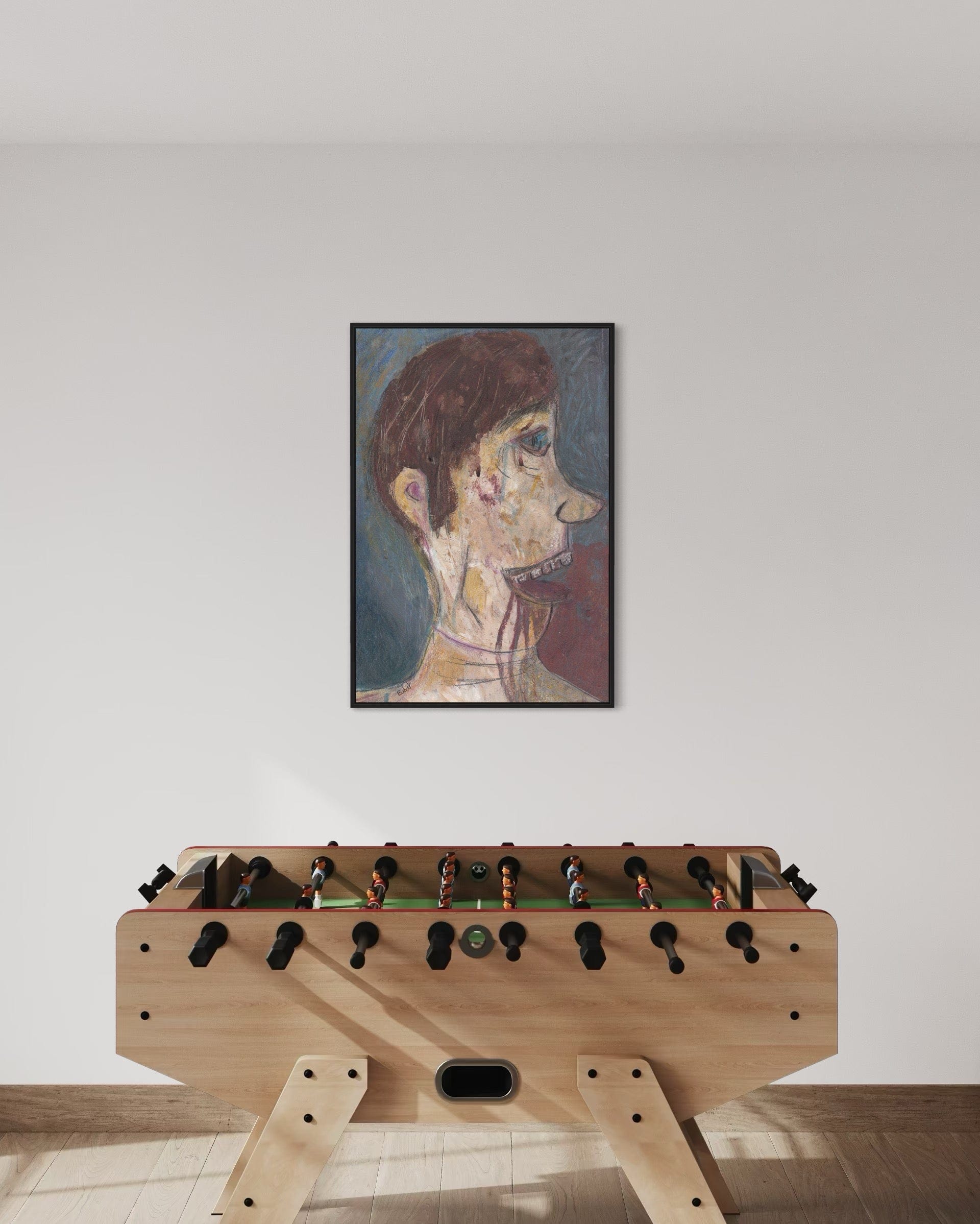 Foosball table with a framed artwork on the wall above it.