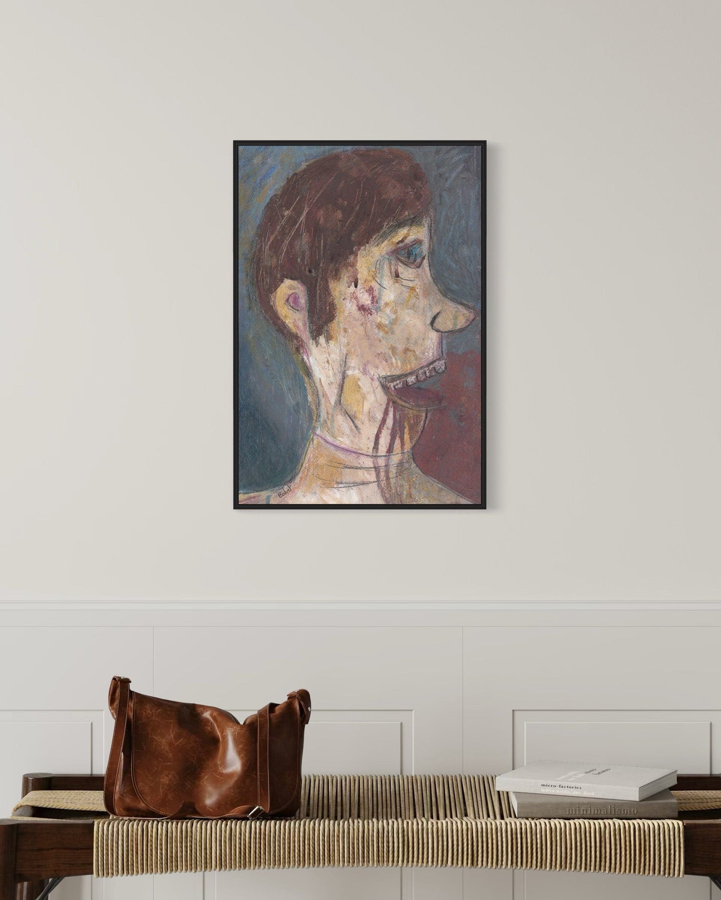 Framed portrait on a wall above a bench with a brown leather bag.