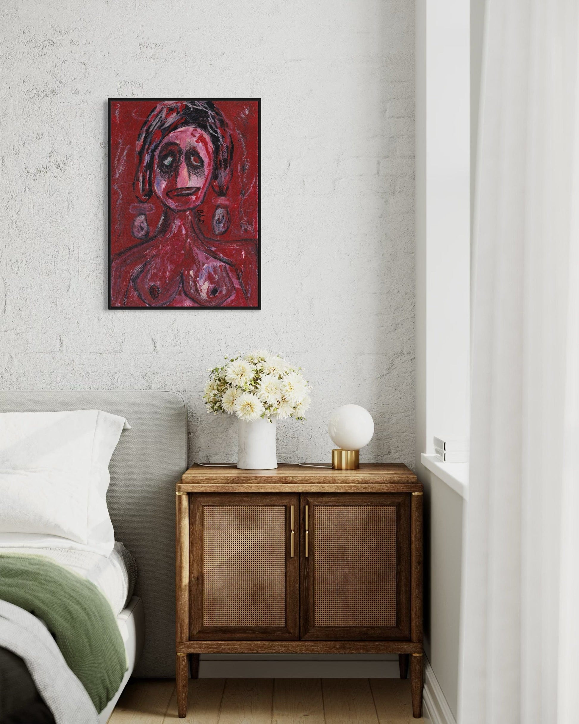 Red abstract painting on a wall above a wooden side table with a lamp and flowers.