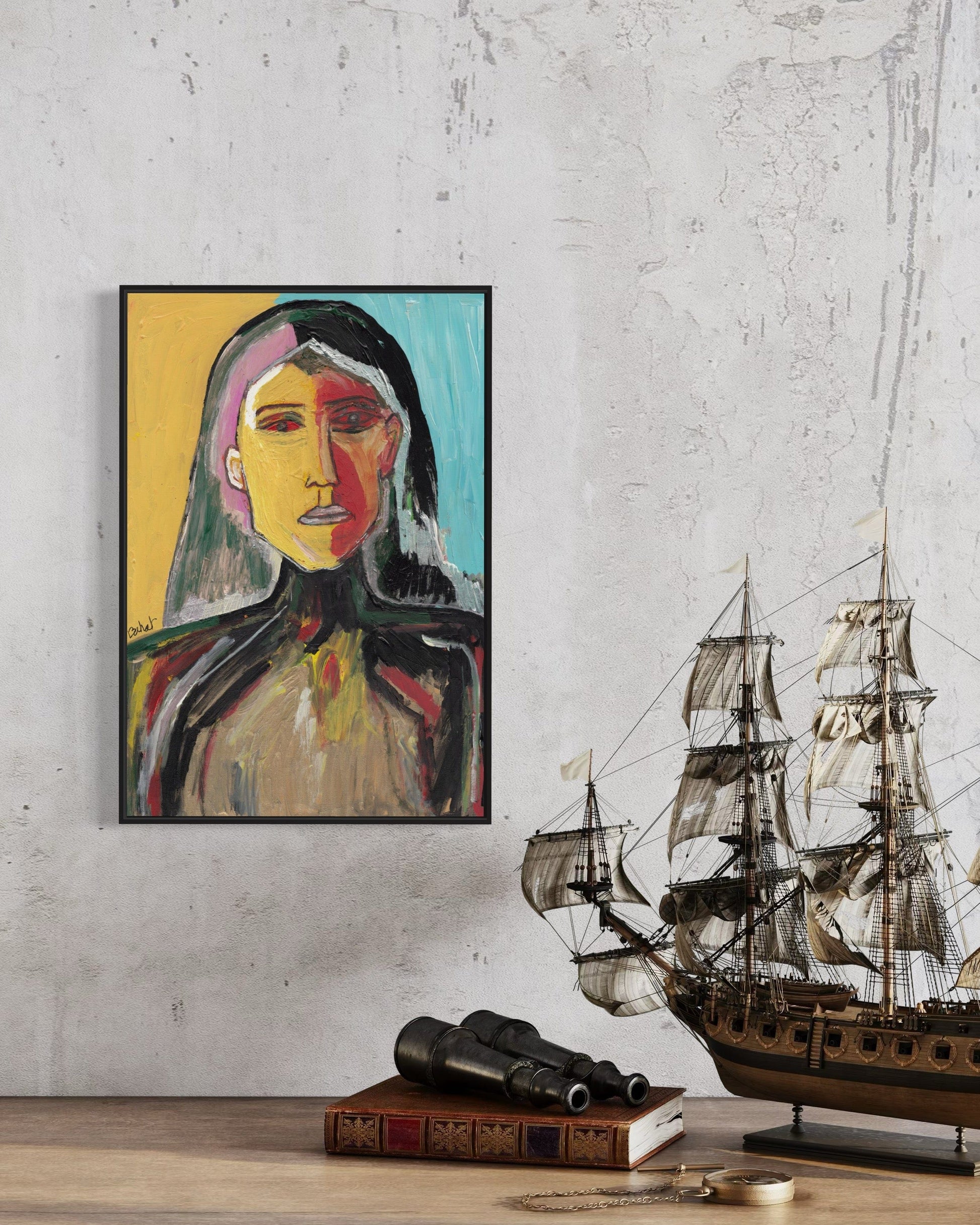 Framed abstract portrait on a wall with a model ship and books below.