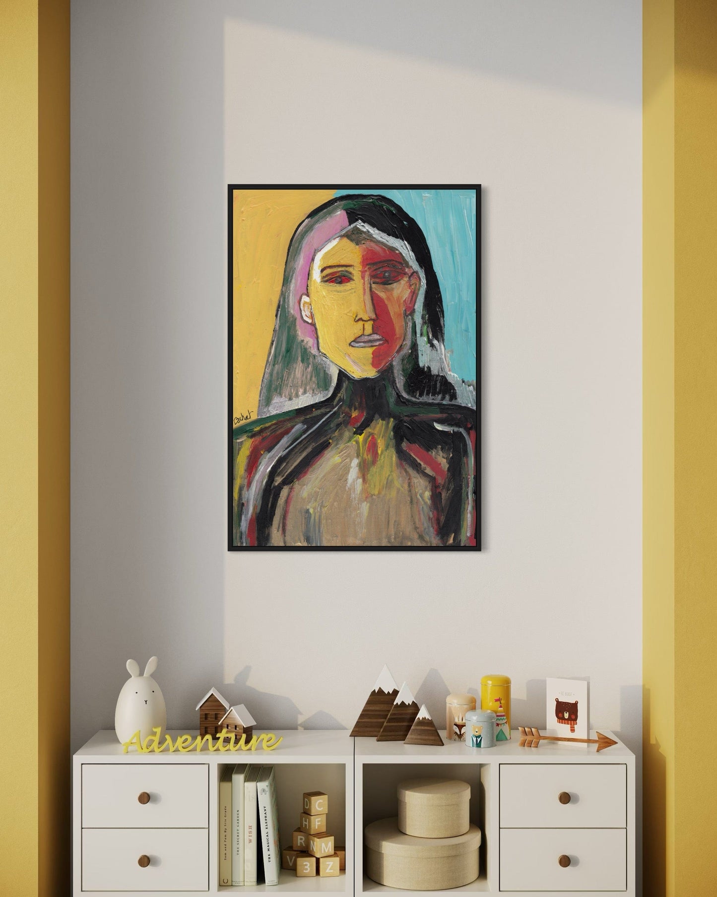 Colorful abstract painting of a woman's face on a wall with yellow walls and a white shelf below.