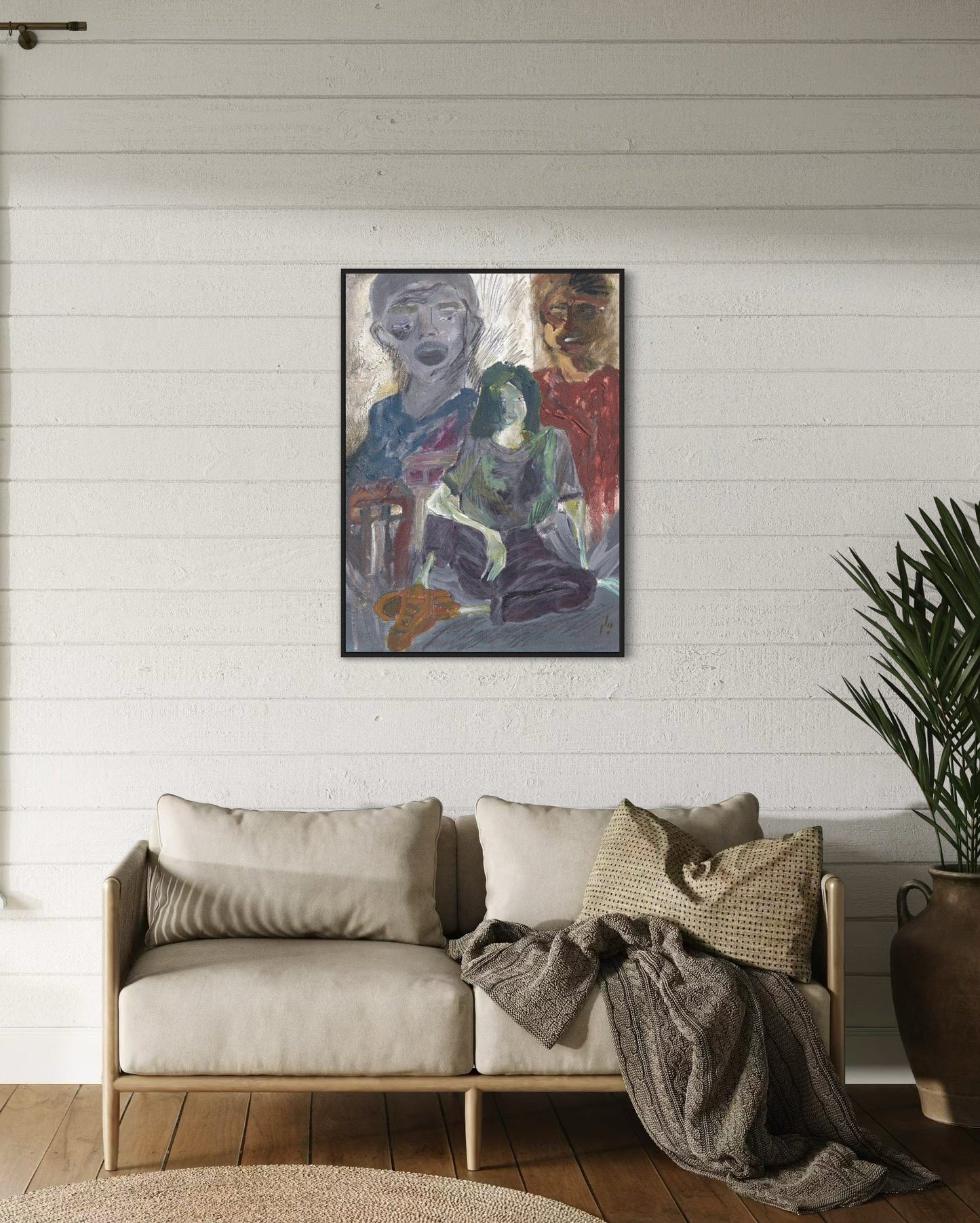 Living room with a couch, plant, and framed abstract painting on a white wall.