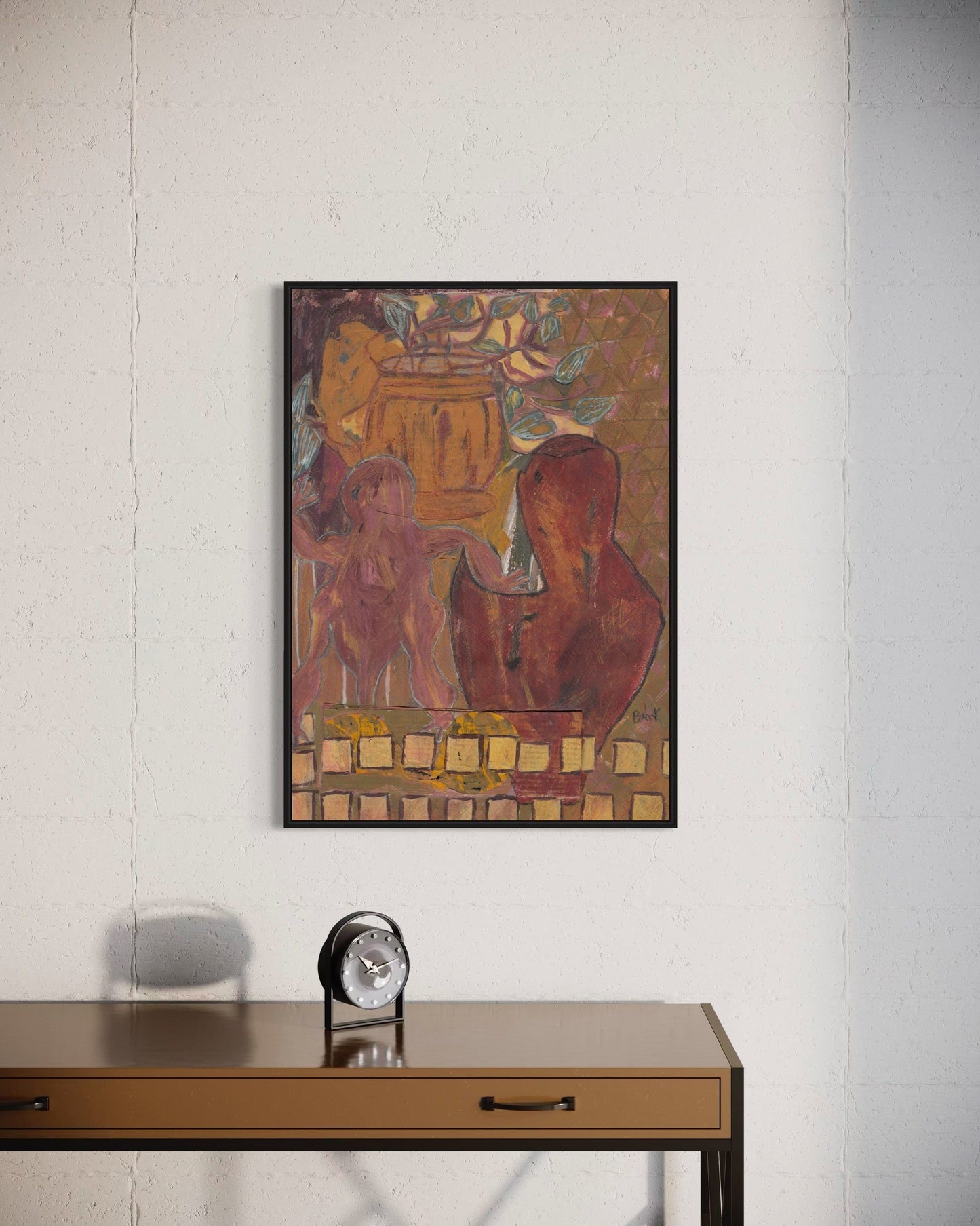 Framed artwork on a wall above a wooden desk with an alarm clock.