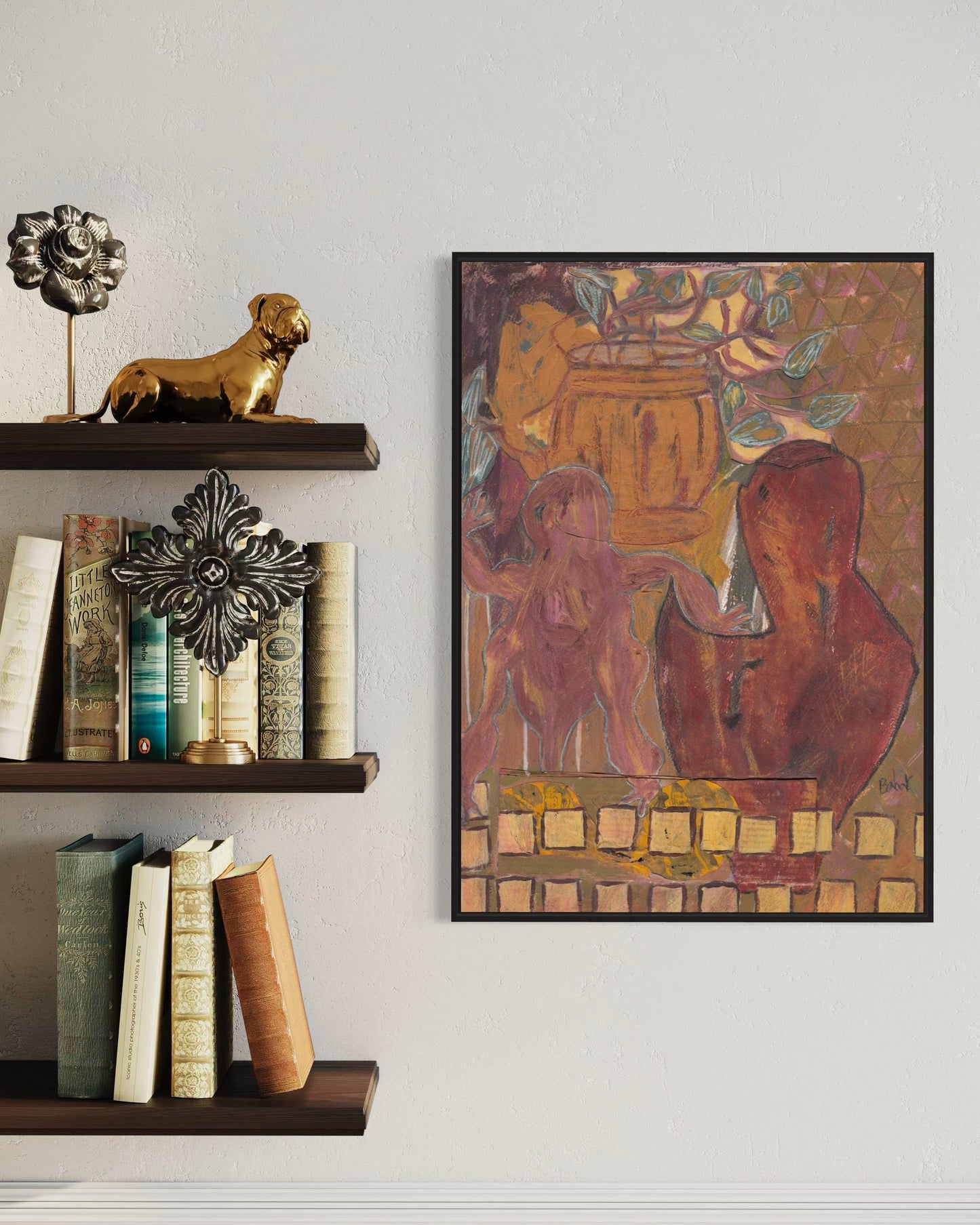 Framed artwork on a wall next to a shelf with books and decorative items.
