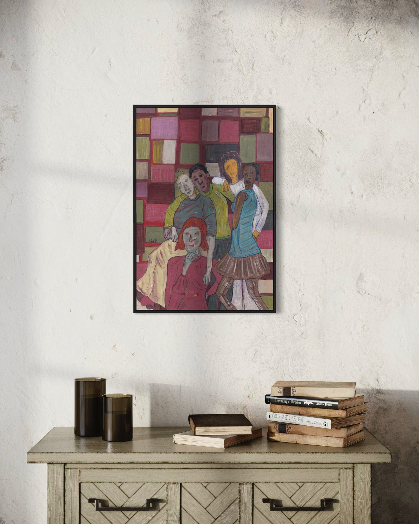 Framed abstract artwork on a textured wall above a wooden cabinet with books.