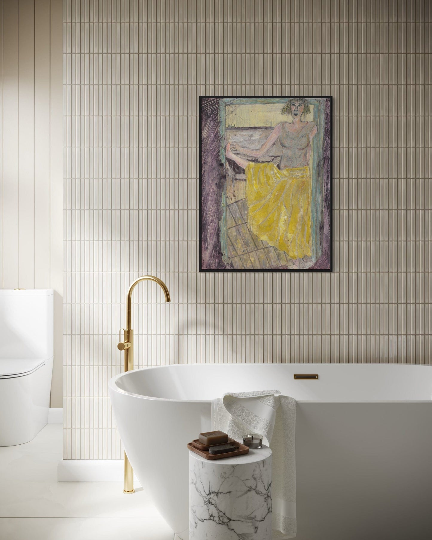 Bathroom interior with a freestanding bathtub, gold faucet, and framed artwork on the wall.