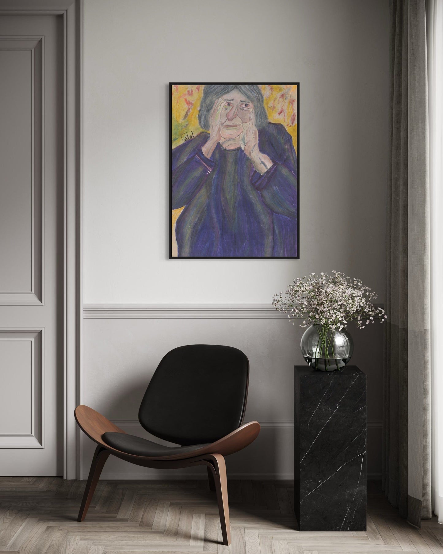 Modern interior with a black chair, side table, and framed artwork on a gray wall.