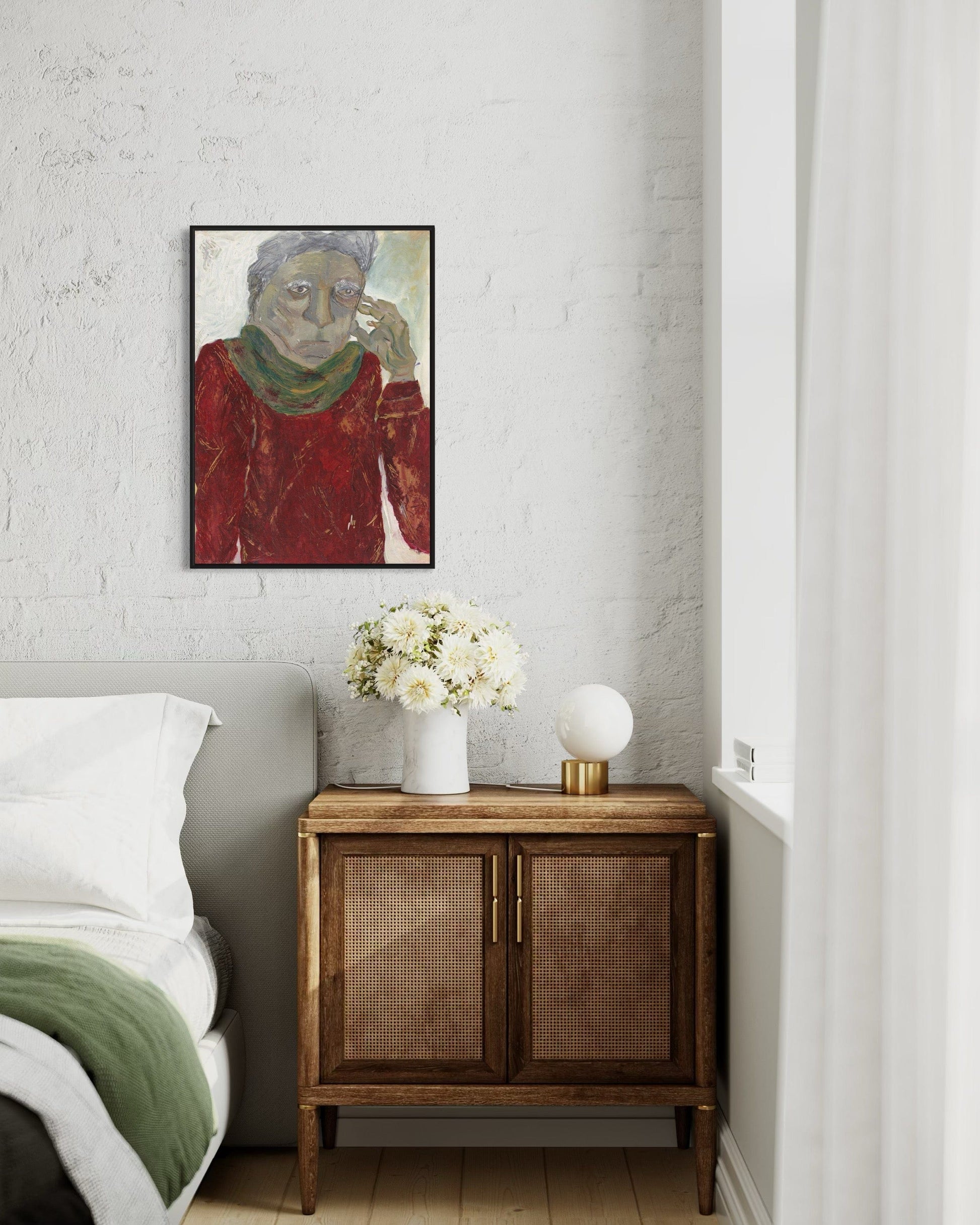 Framed artwork above a wooden cabinet with a vase of flowers in a bedroom setting.
