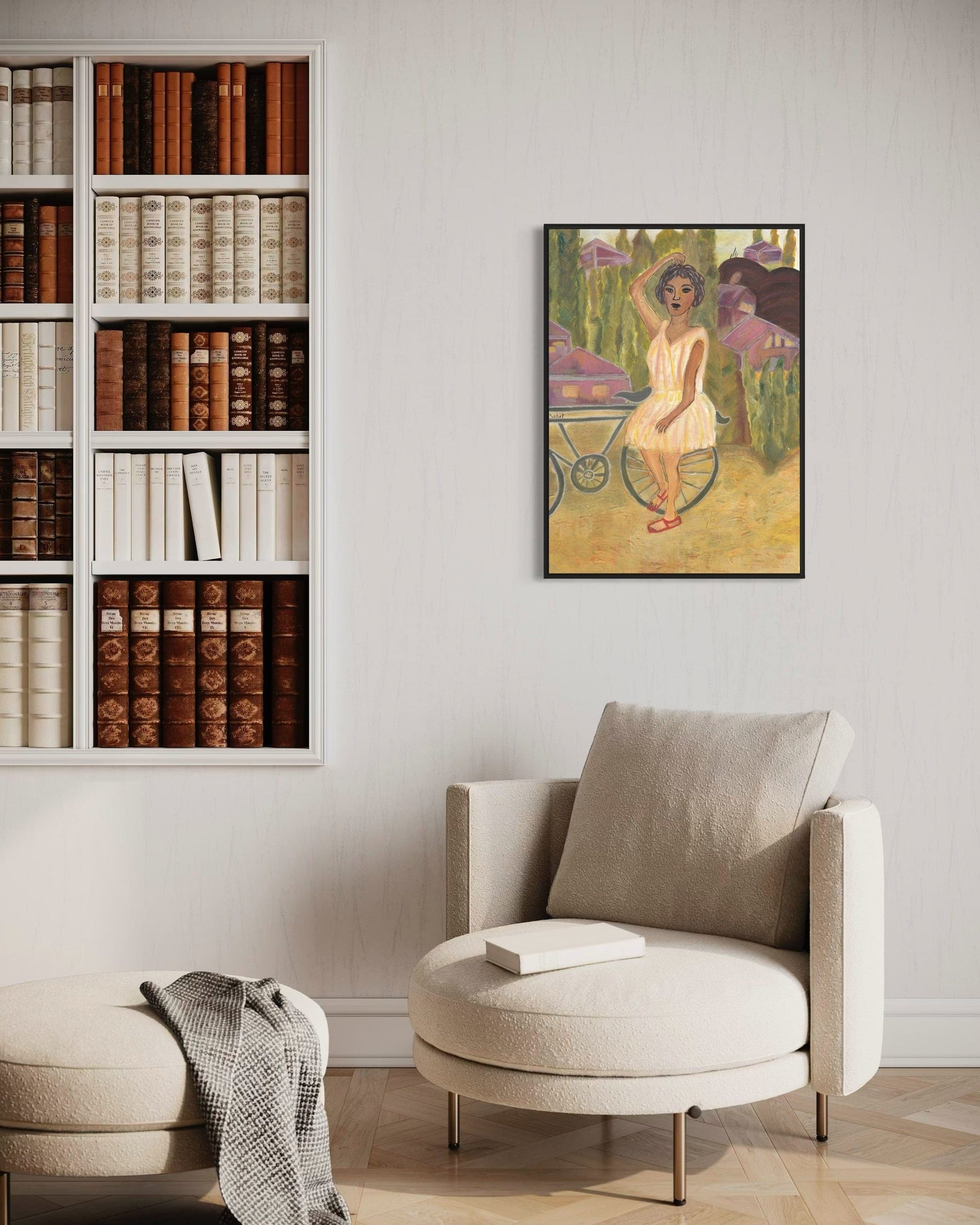 Modern living room with a bookshelf, armchair, and framed artwork on the wall.