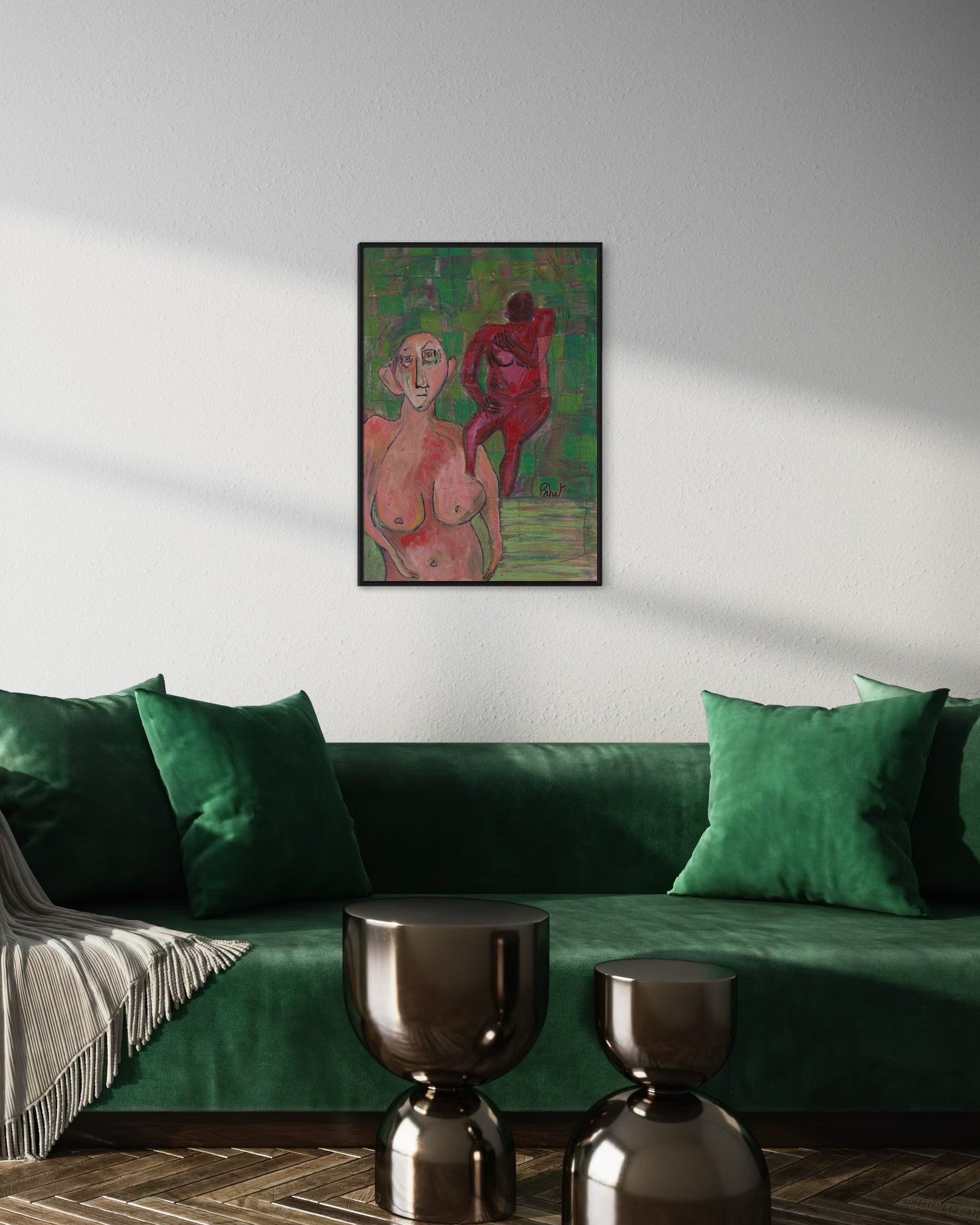 Framed artwork of two nude figures on a wall above a green sofa.