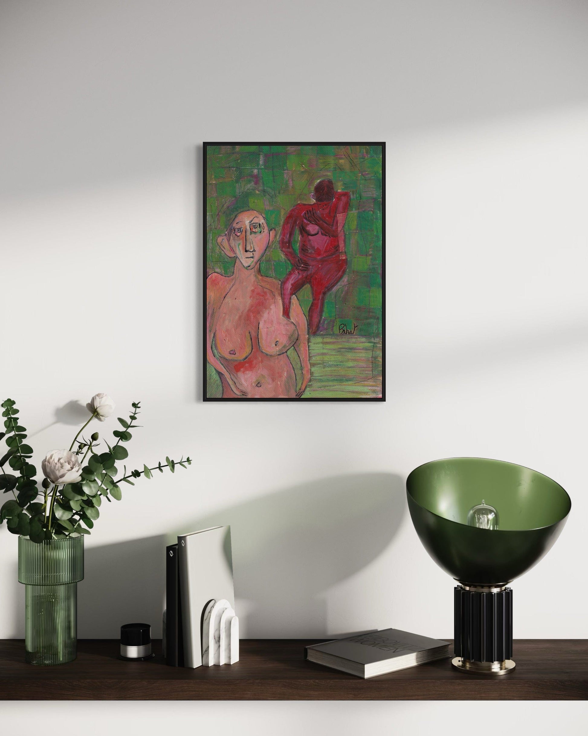 Framed artwork of two nude figures on a wall above a wooden surface with decorative items.