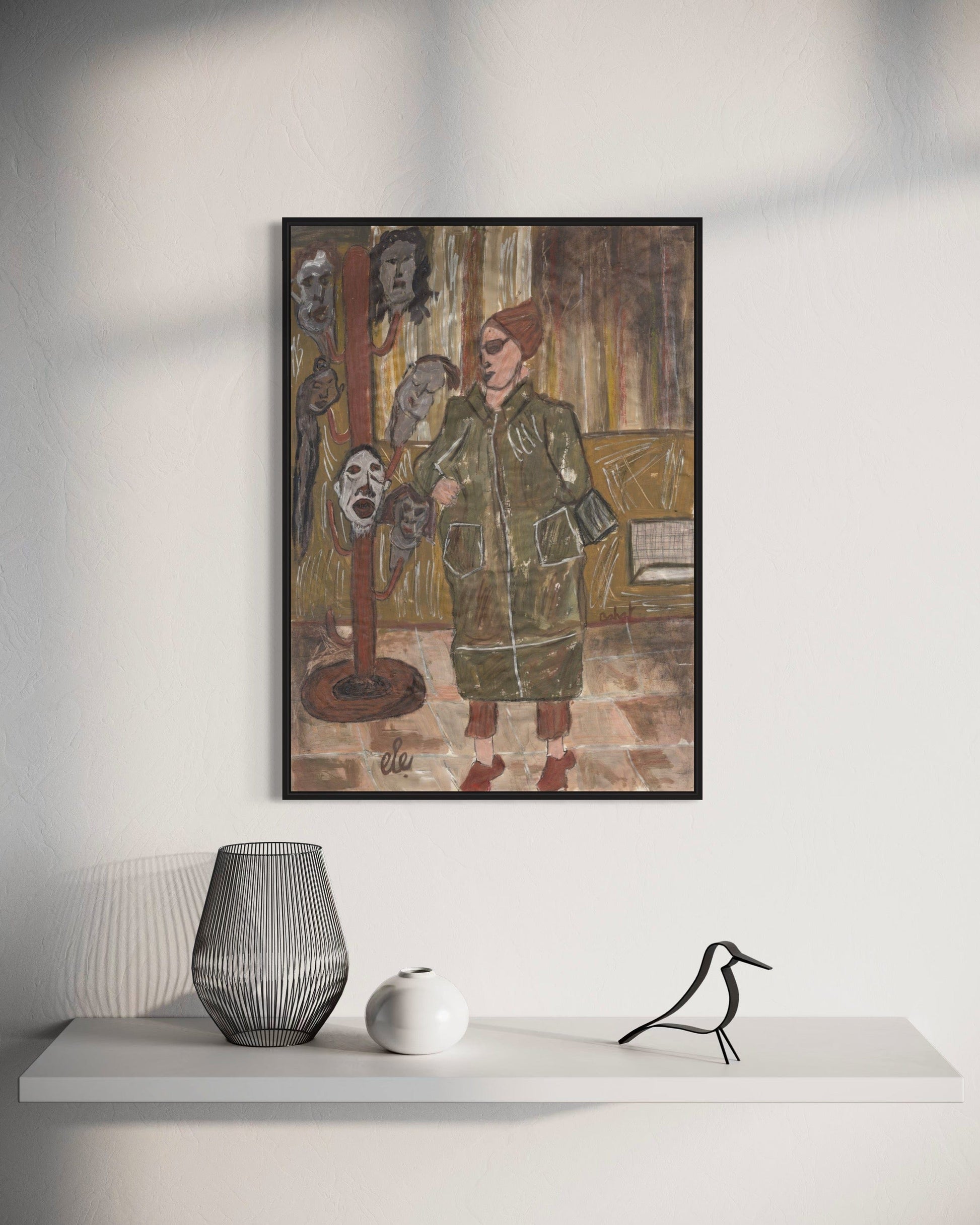 Framed artwork on a wall above a white shelf with decorative items.
