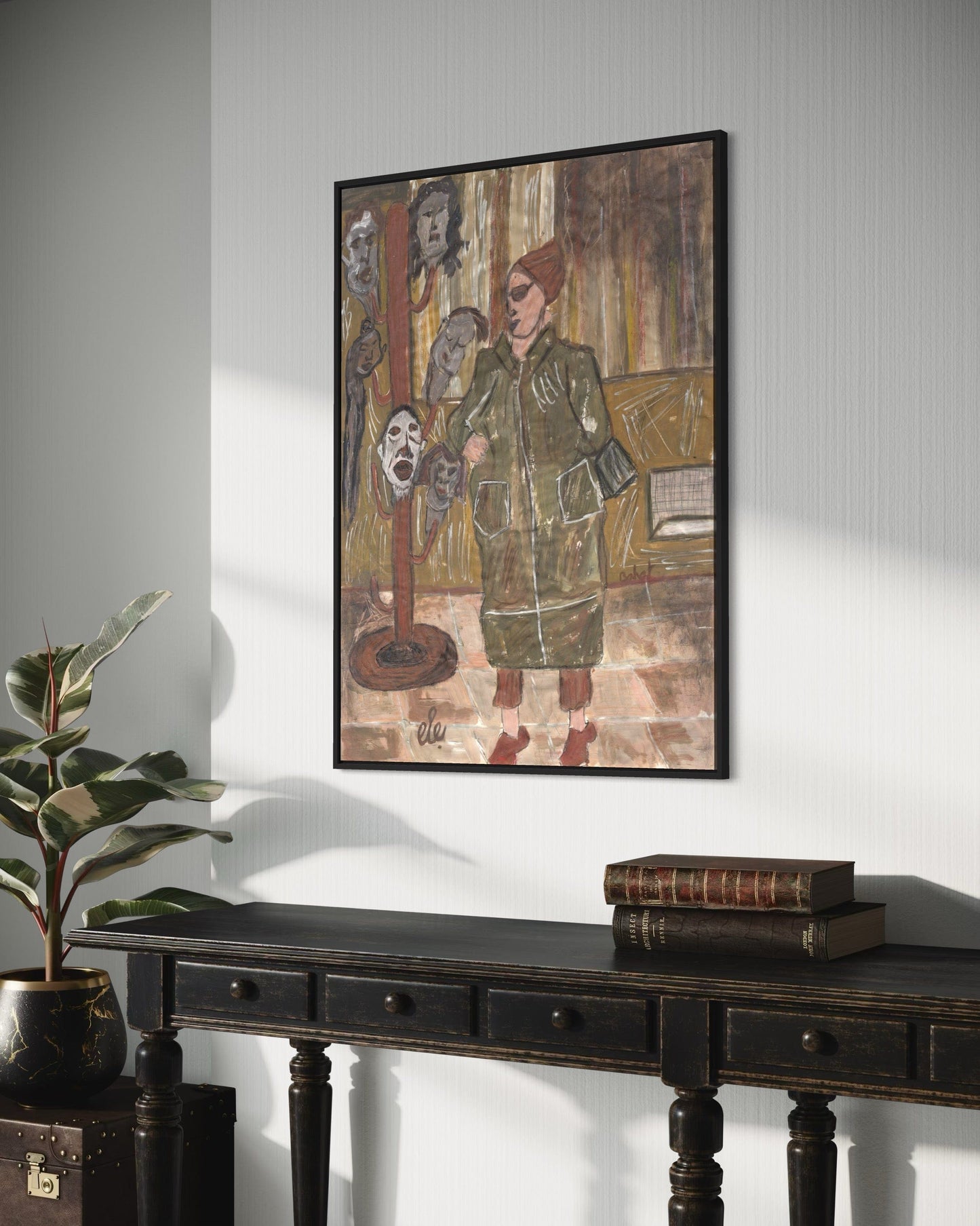 Framed artwork on a wall above a dark wooden console table with books and a plant.