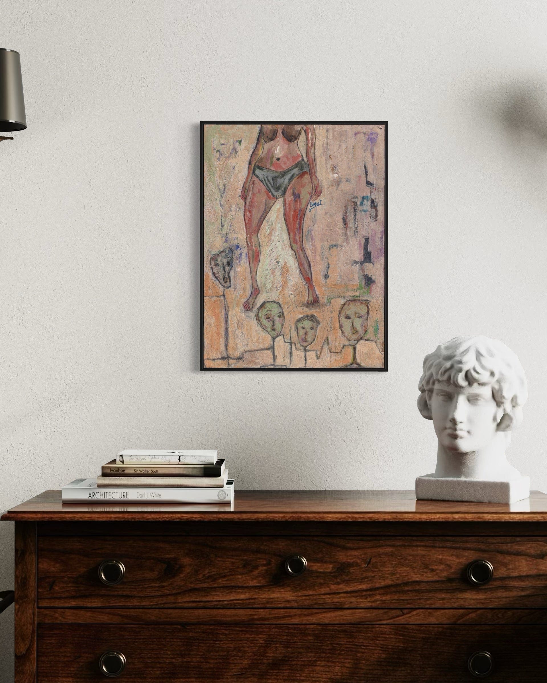 Framed abstract artwork on a wall above a wooden dresser with books and a sculpture.