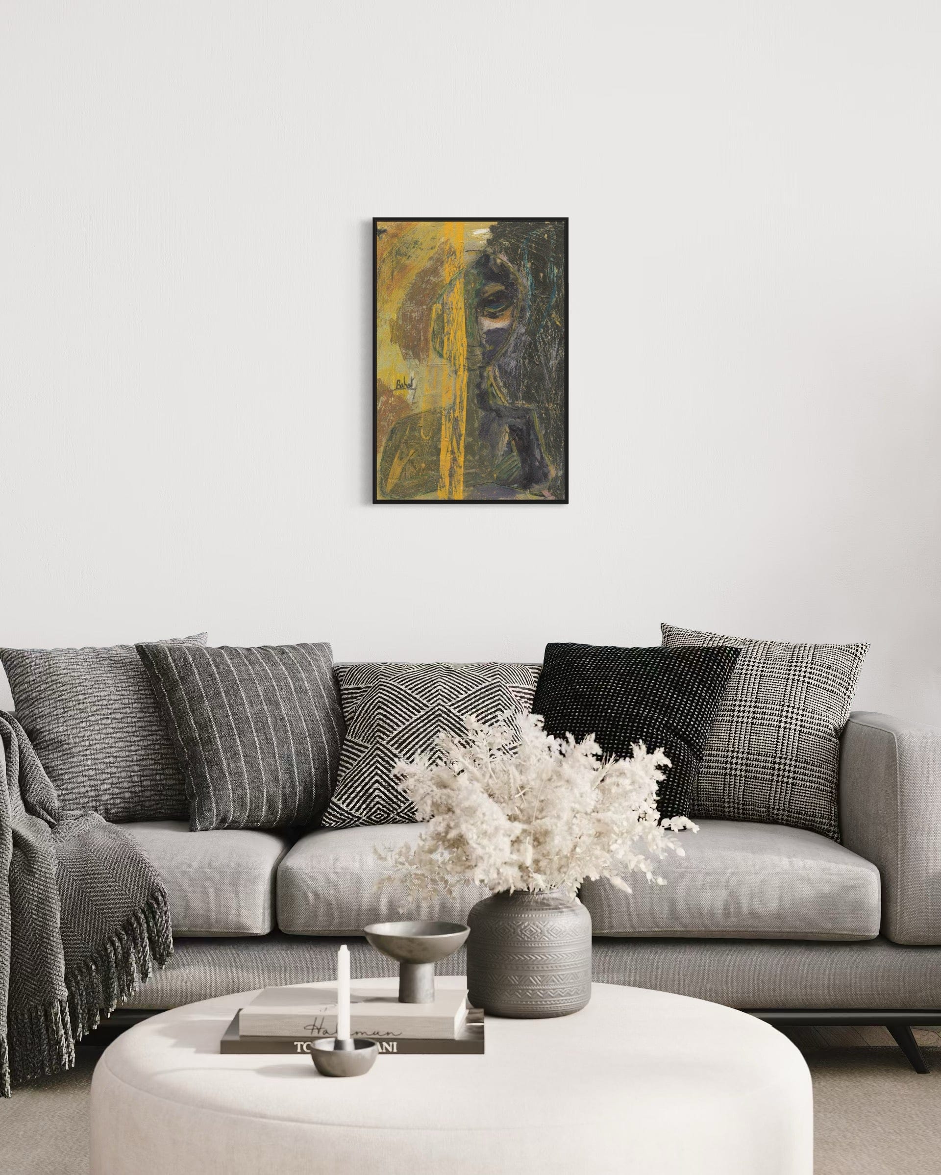 Living room with a gray sofa, decorative pillows, a vase with flowers, and a framed abstract painting on the wall.