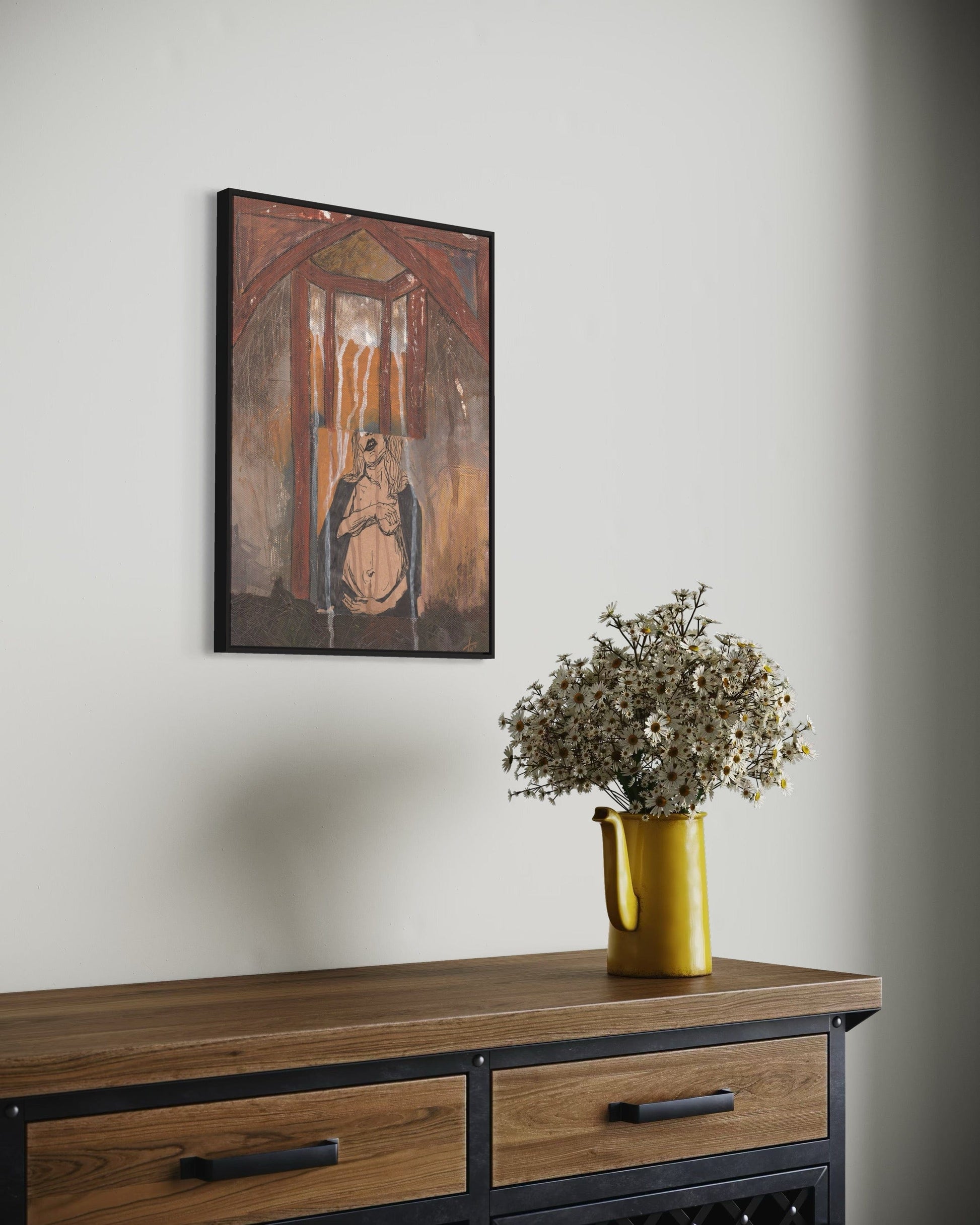 Framed artwork above a wooden console table with a yellow vase holding flowers.
